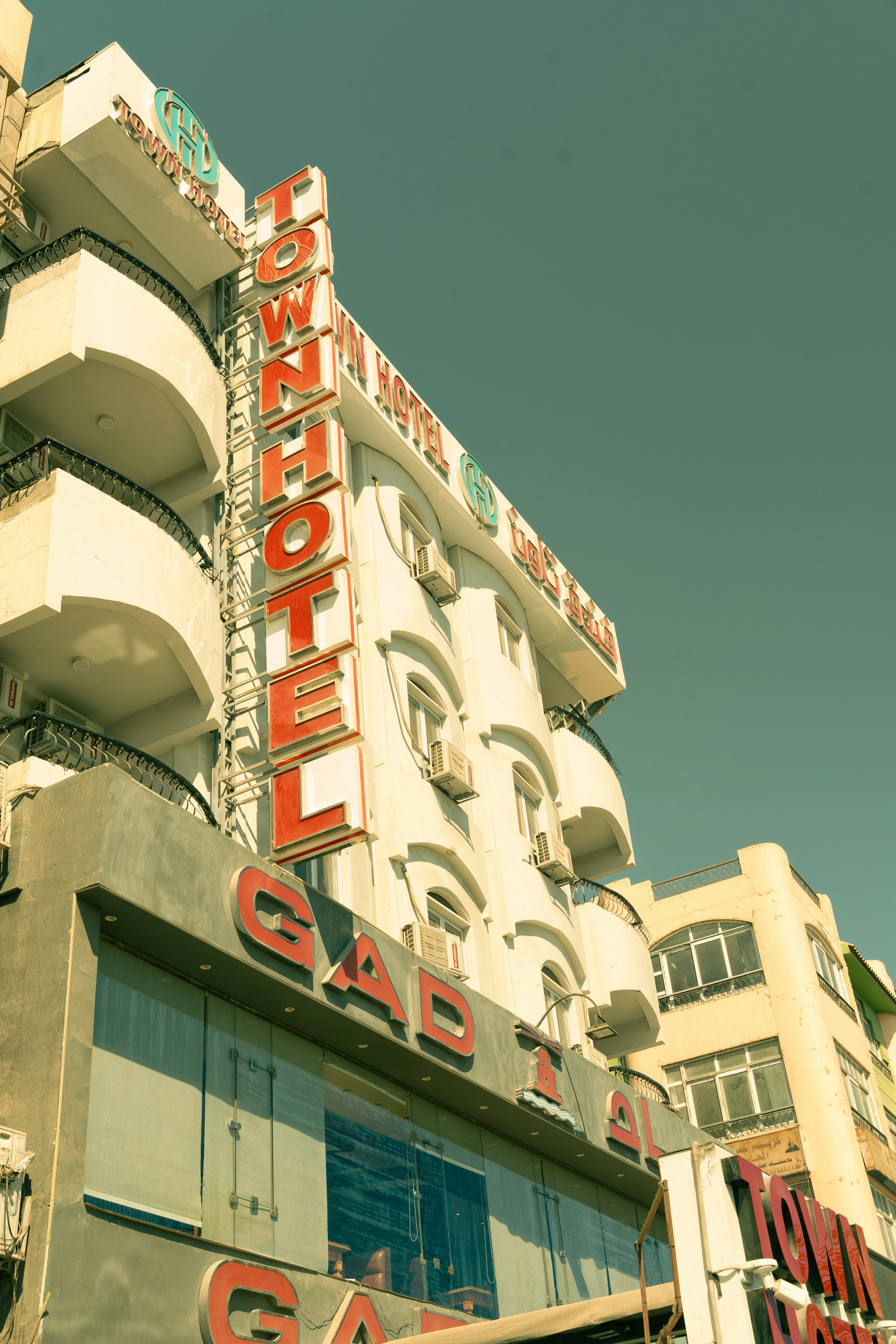 A vertical sign reading Town Hotel on the facade of a white building under a clear sky