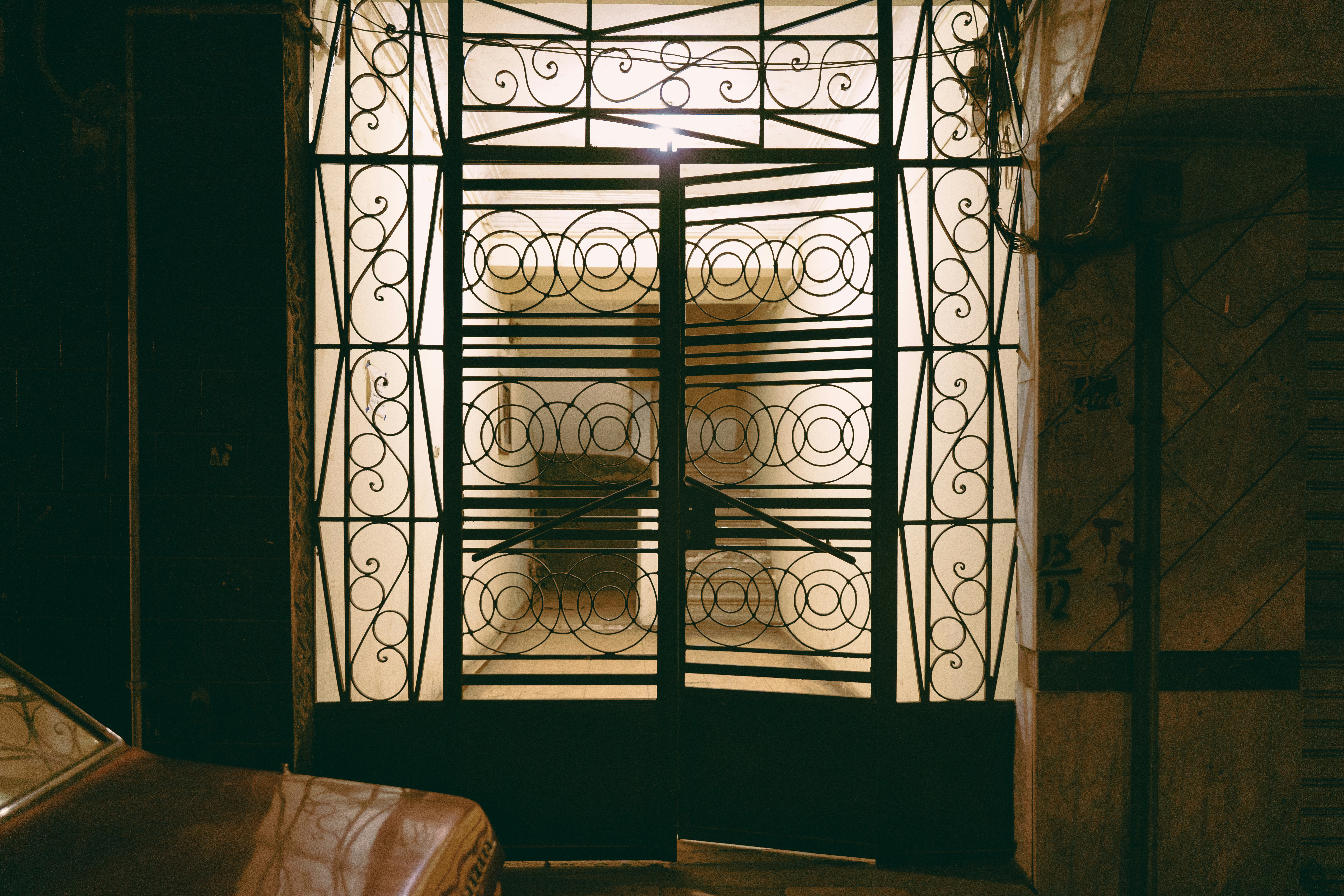 A decorative black metal gate with circular patterns in front of a brightly lit building entrance