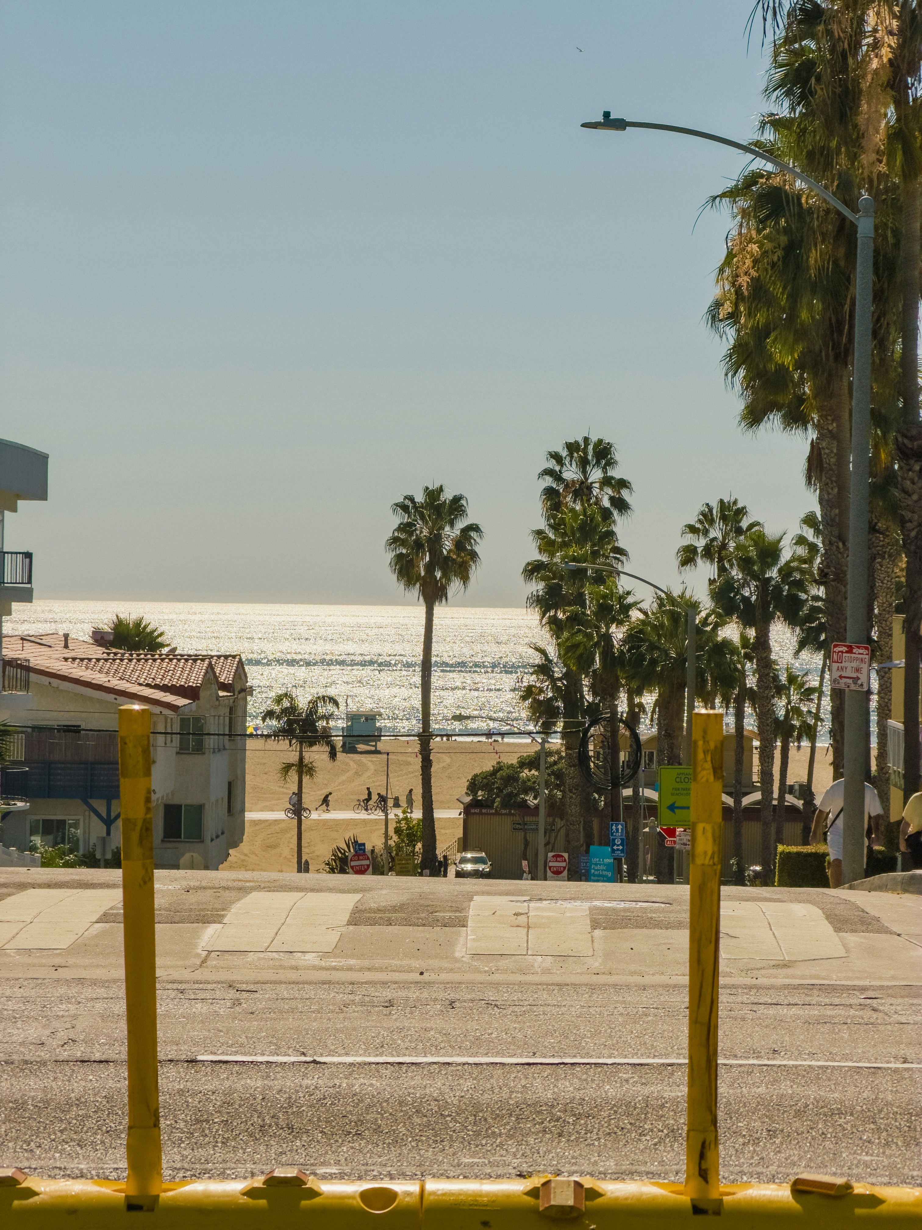 Una vista lungo una strada verso una spiaggia sabbiosa con palme e acqua scintillante dell'oceano