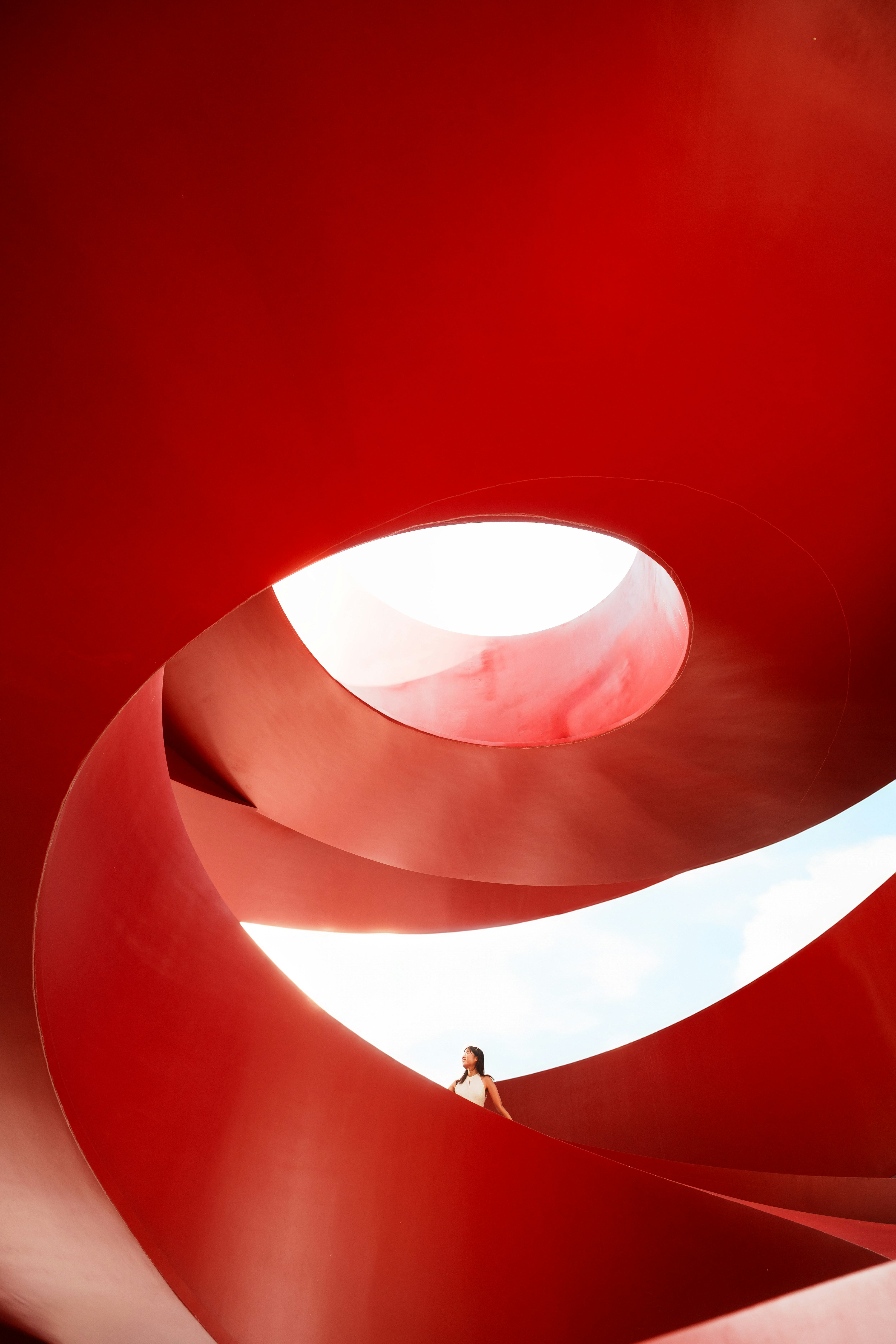 A person in a white top standing inside a large red spiral structure