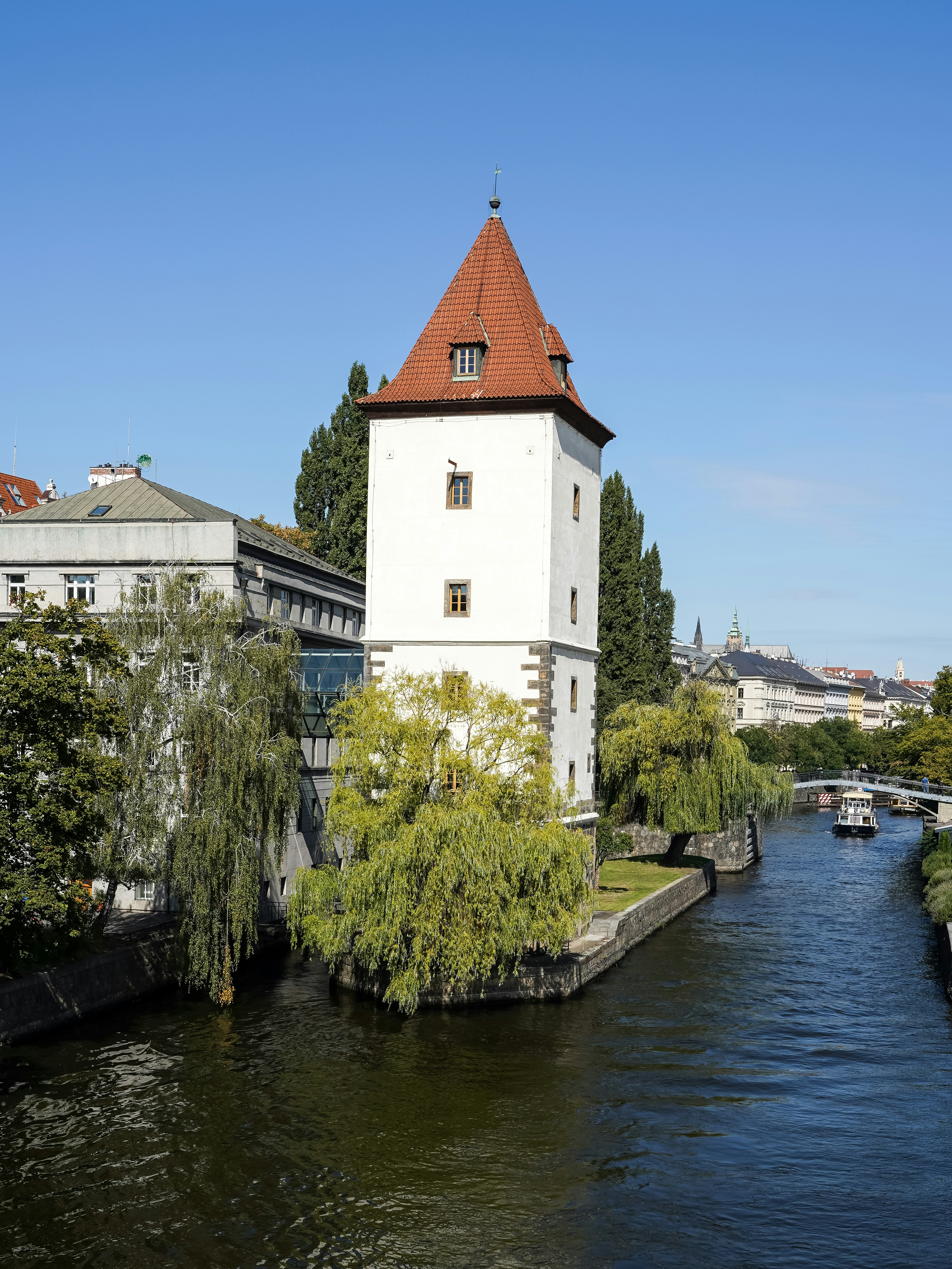 The white Malostranská water tower with a red roof beside a canal in Prague