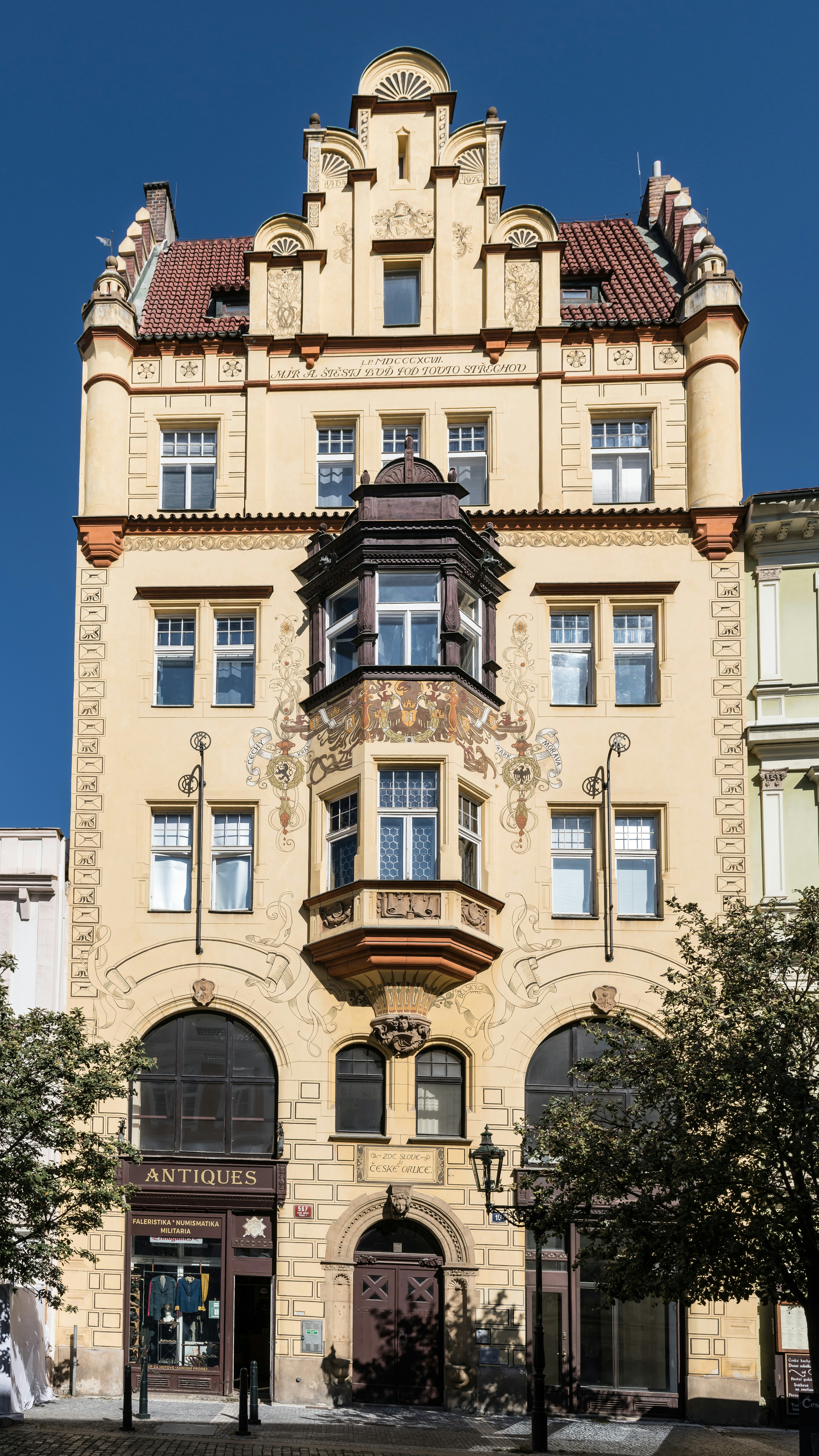 An ornate yellow building with a central bay window and decorative murals in Prague