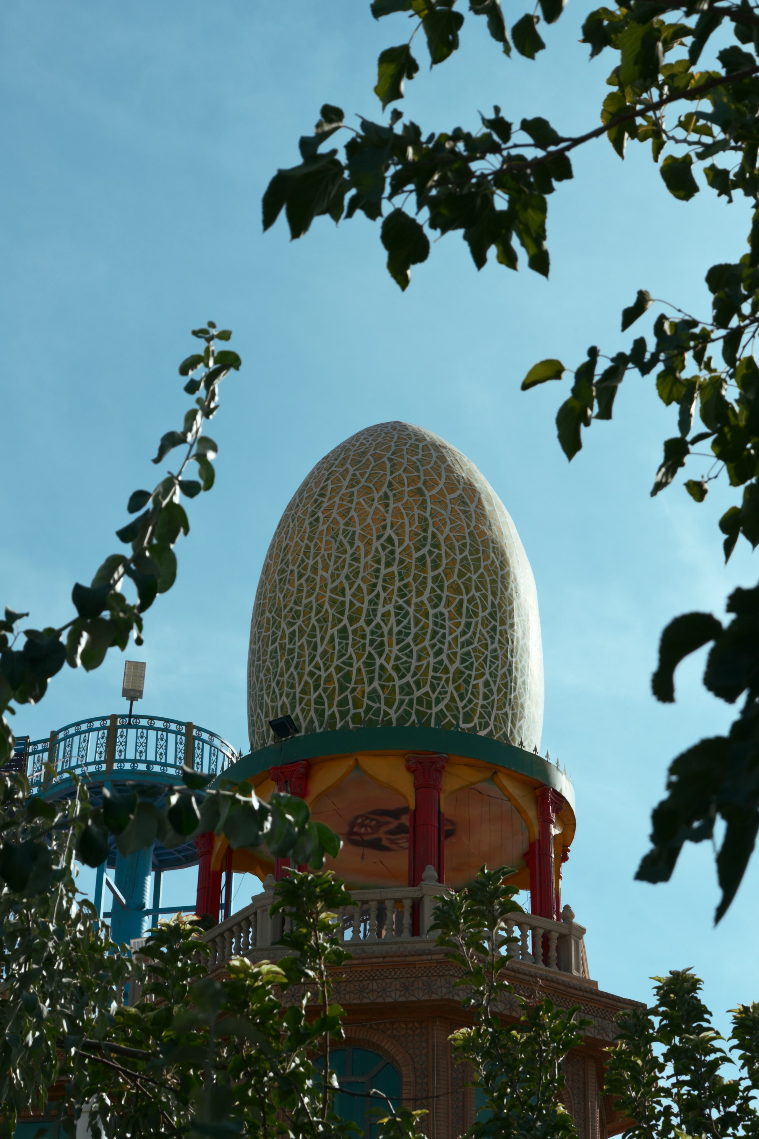 A large egg-shaped structure with a green and white mosaic pattern atop a building