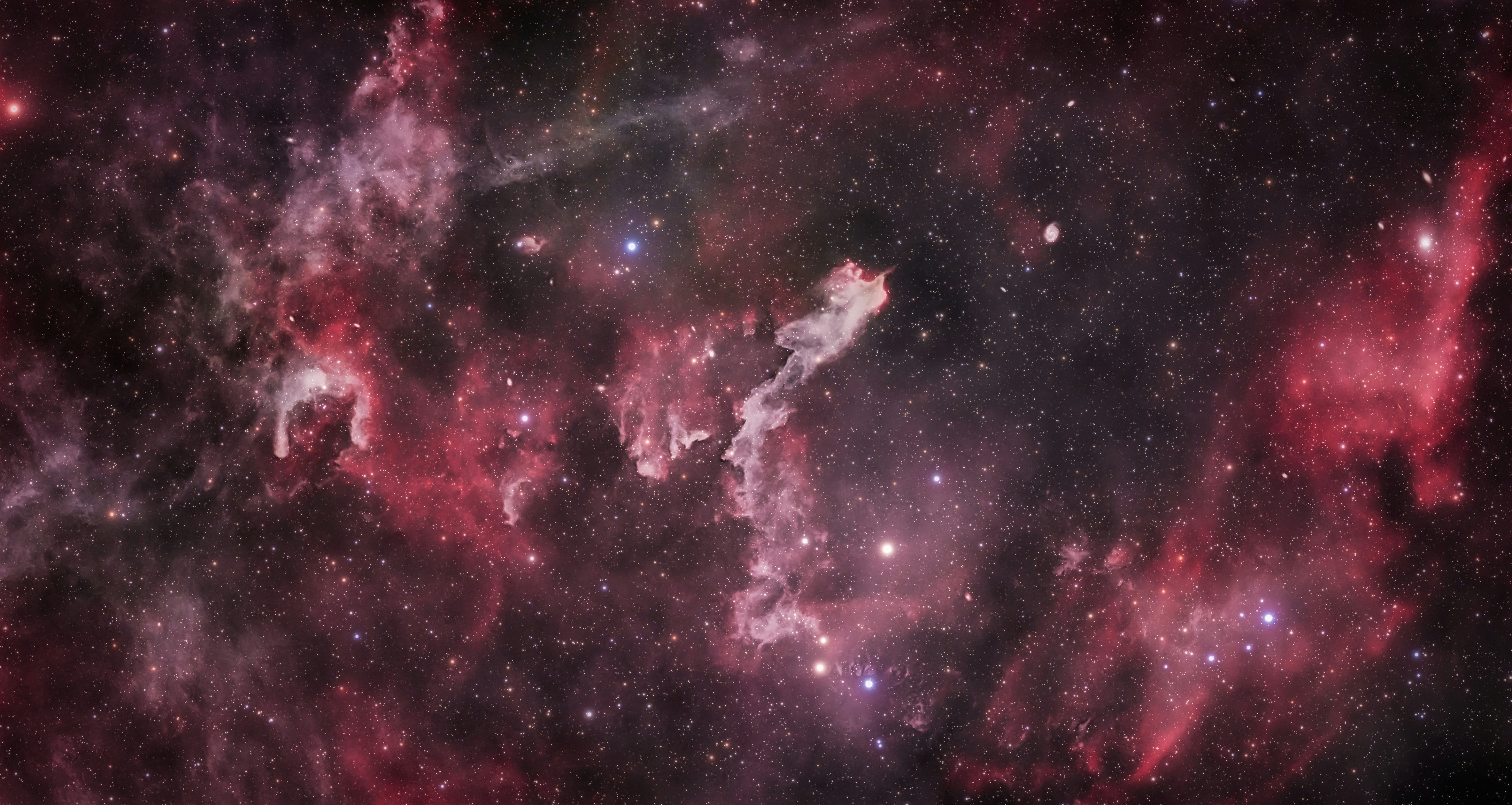 The Sandworm Nebula glowing in deep space with scattered stars and red cosmic dust