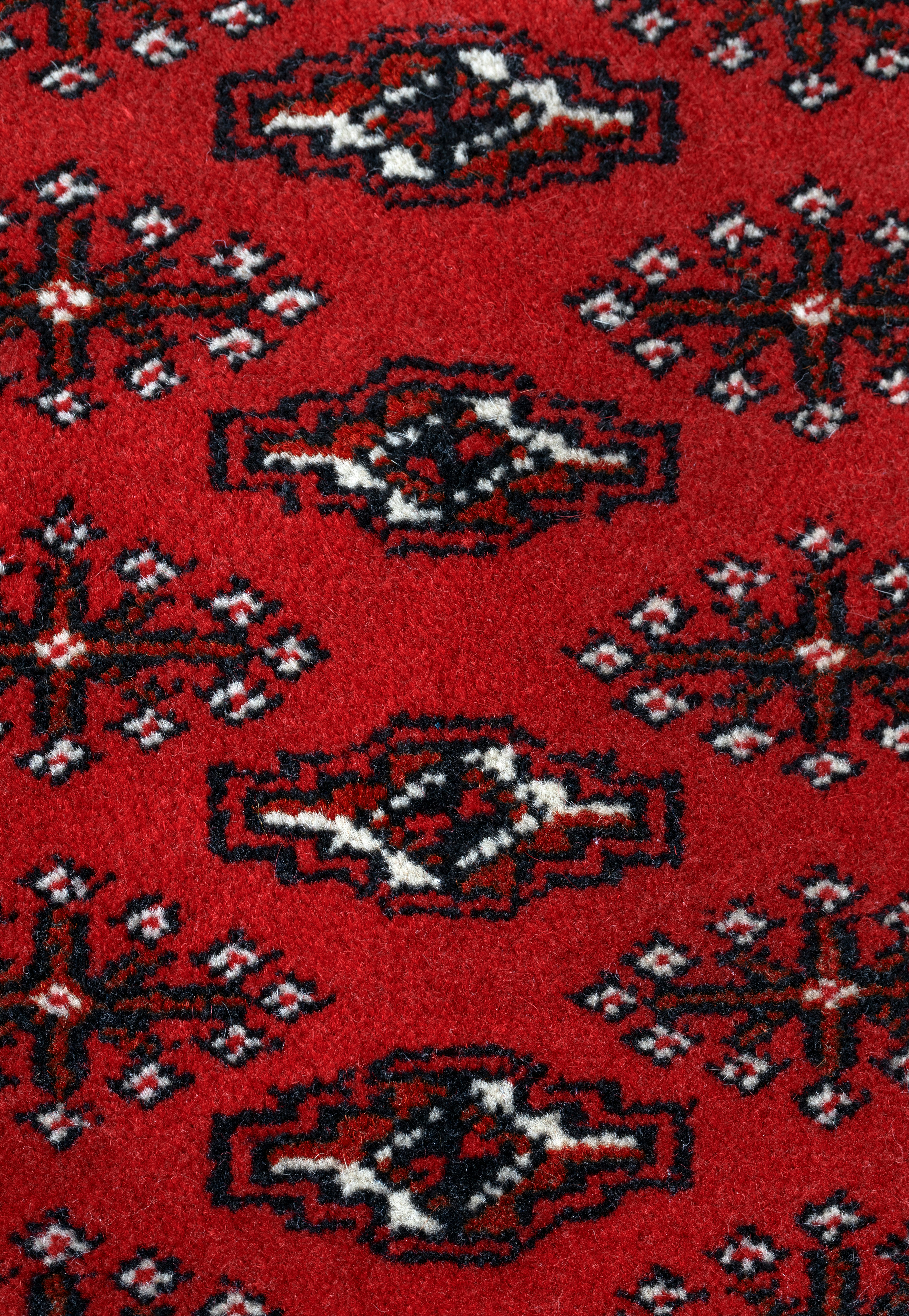 A red wool rug with a repeating black and white geometric pattern
