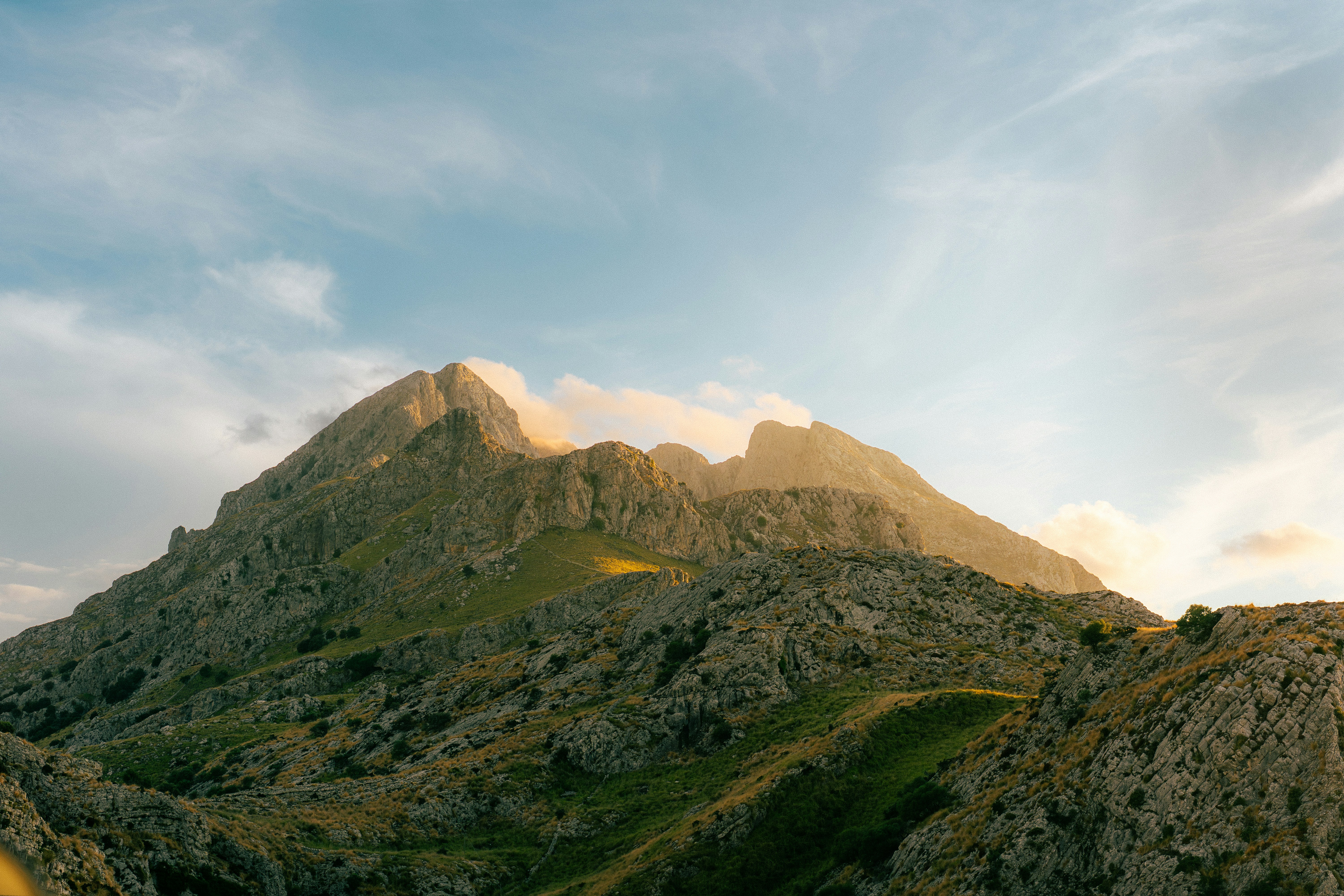 Rocky mountain peaks under a soft blue sky with warm golden light