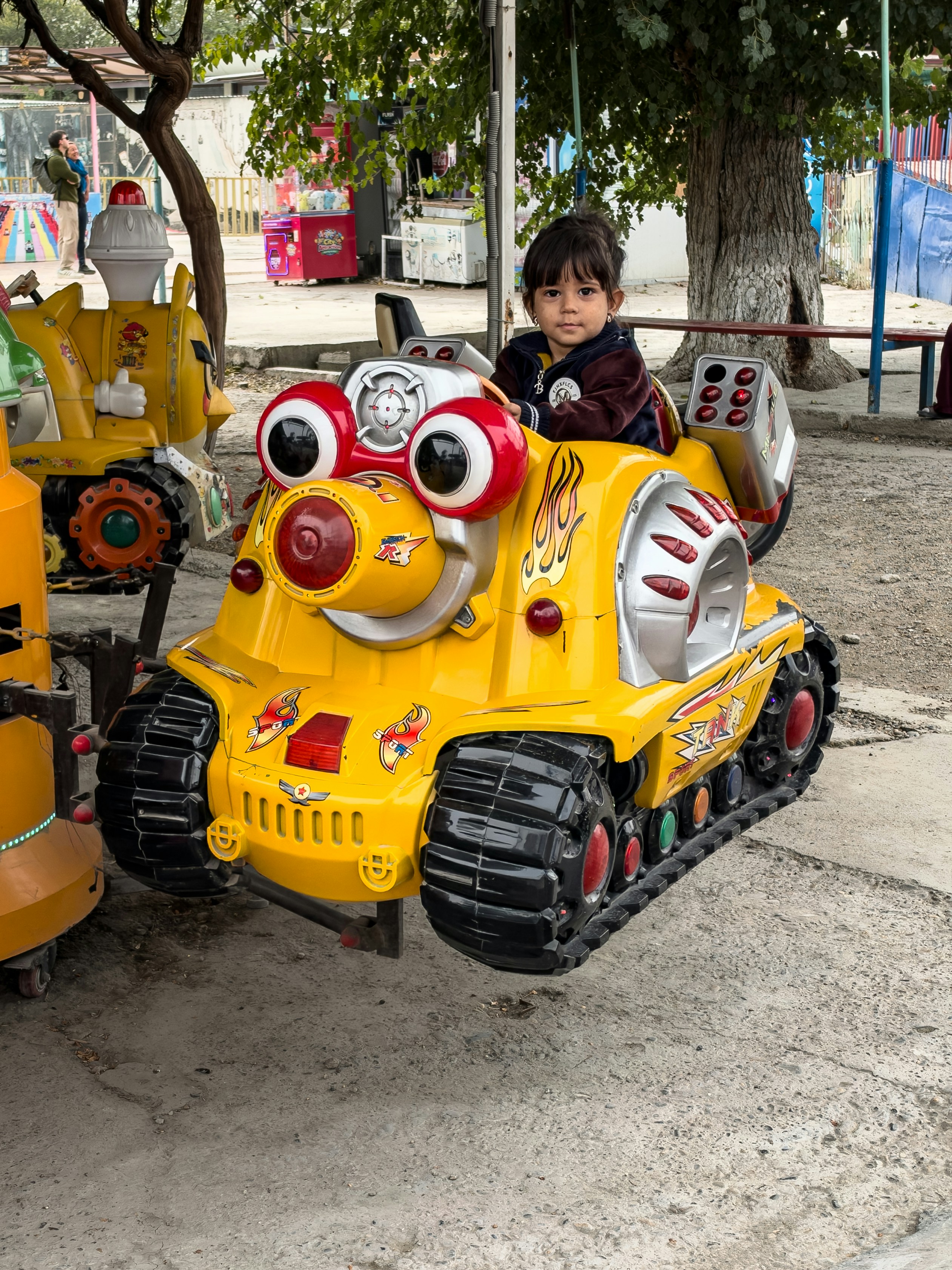 公園の黄色い戦車型の遊具に座る子供