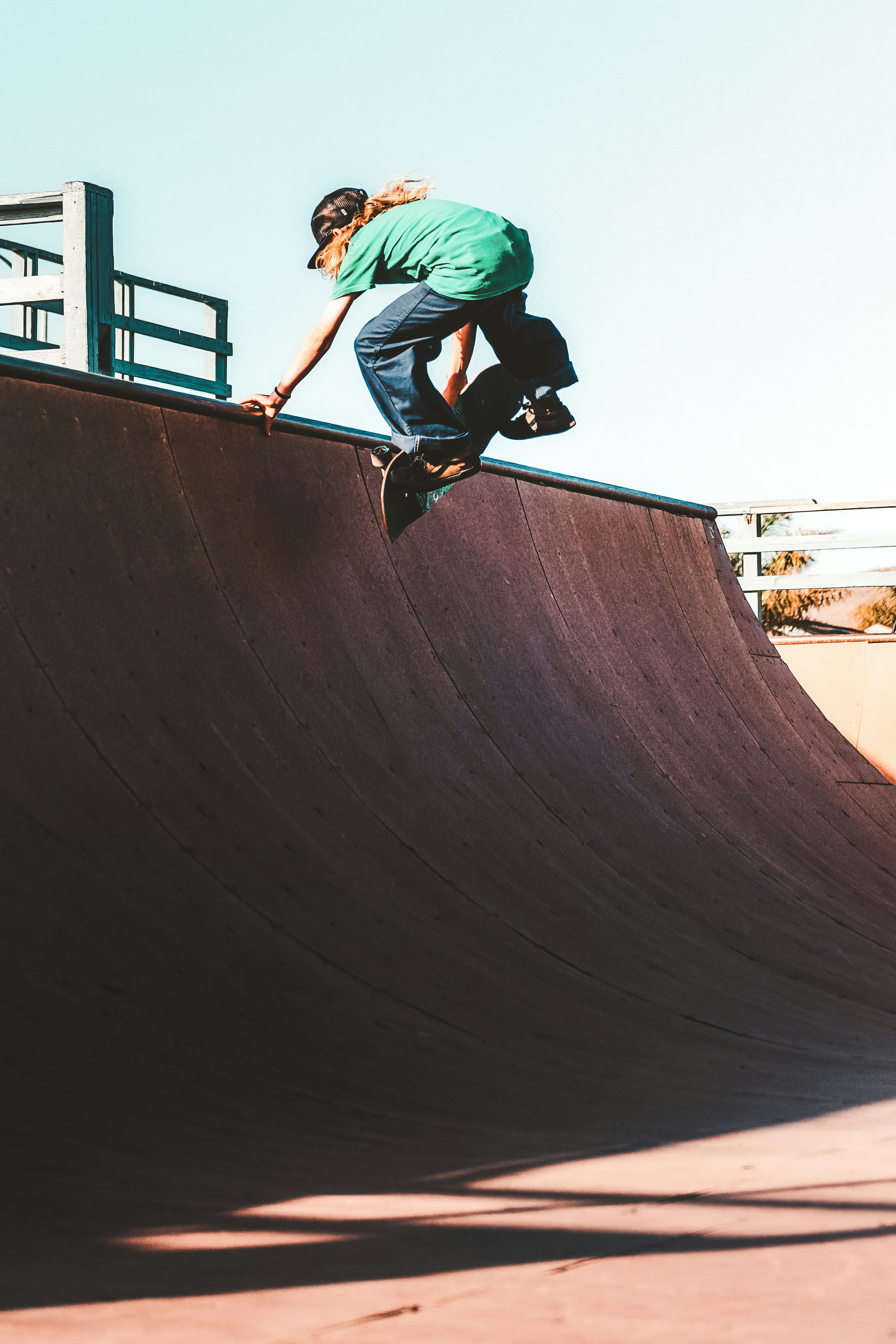 A person in a green t-shirt skateboarding on a halfpipe ramp in Cayucos