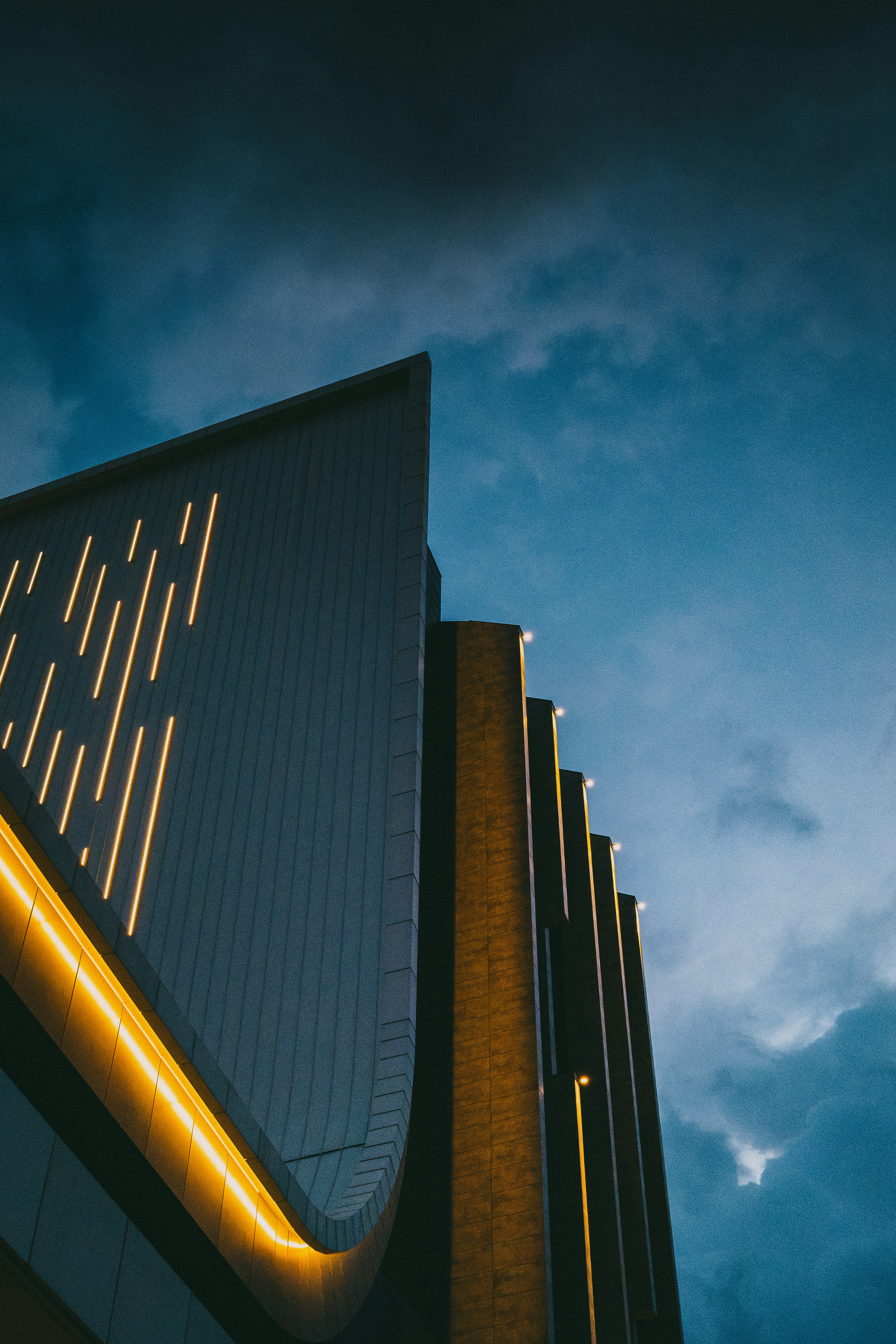 Modern building facade with vertical glowing lights against a deep blue twilight sky
