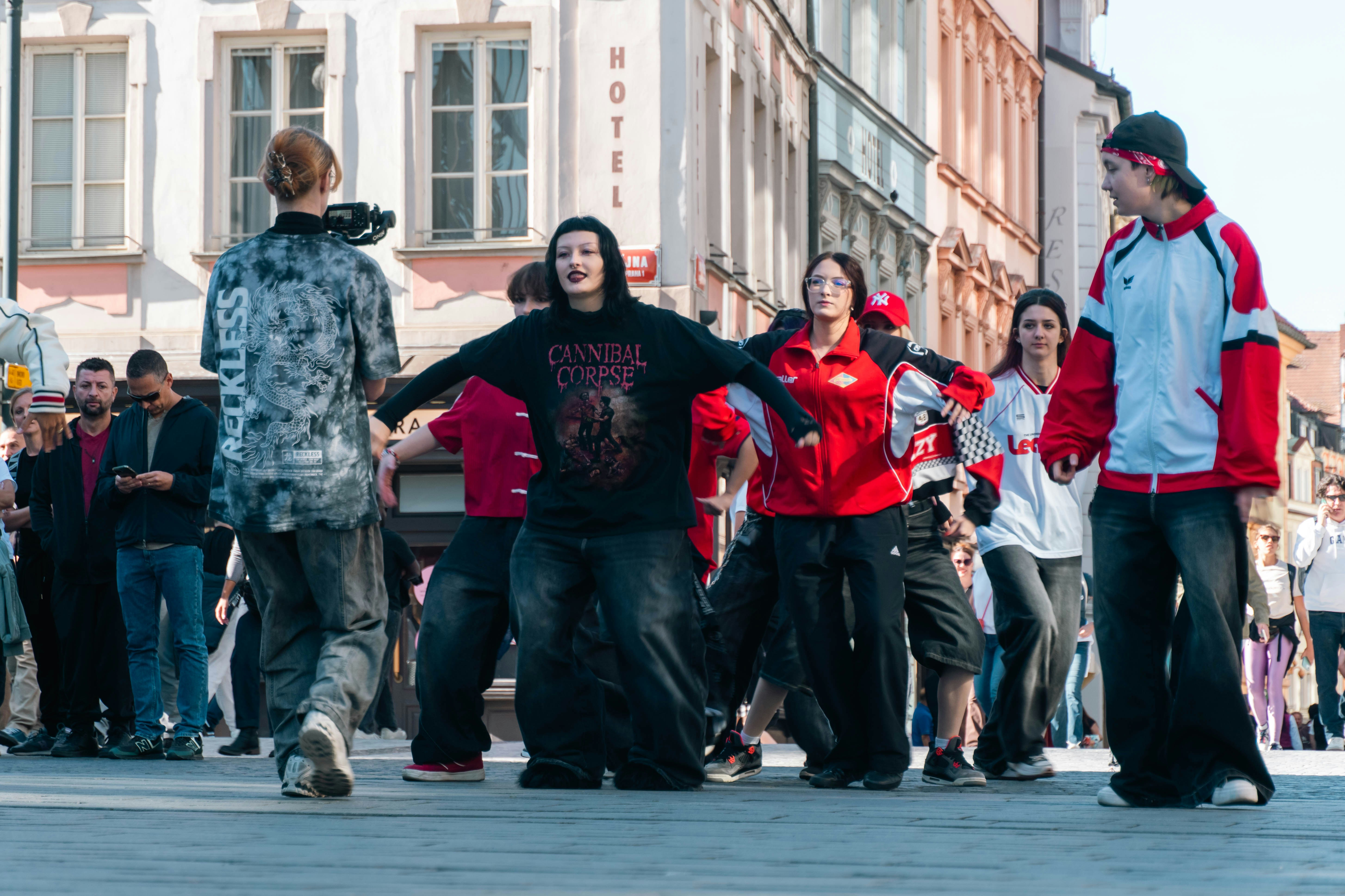 A group of young people dancing in a city square with buildings in the background