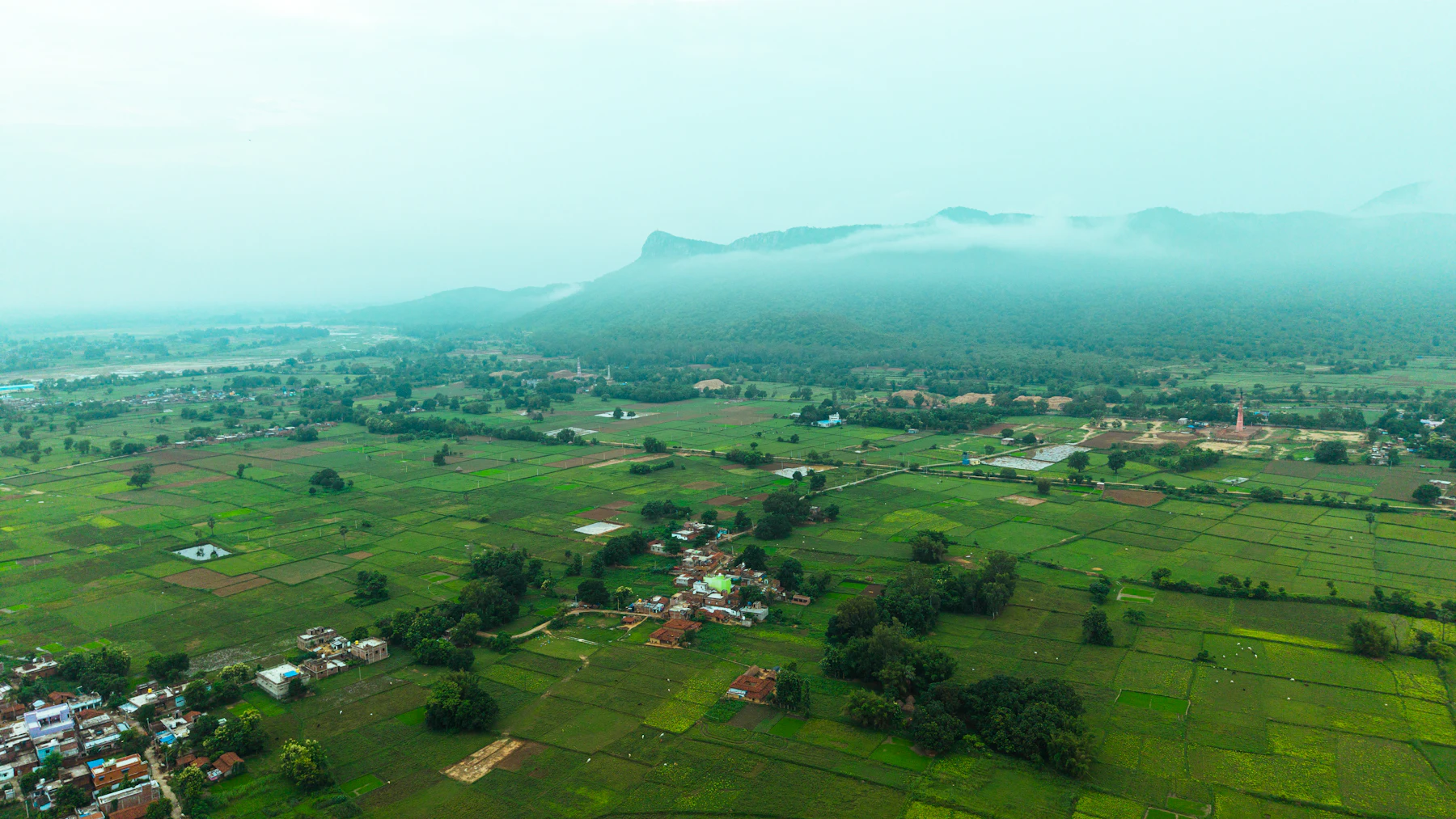 Aerial view of a rural village surrounded by green fields