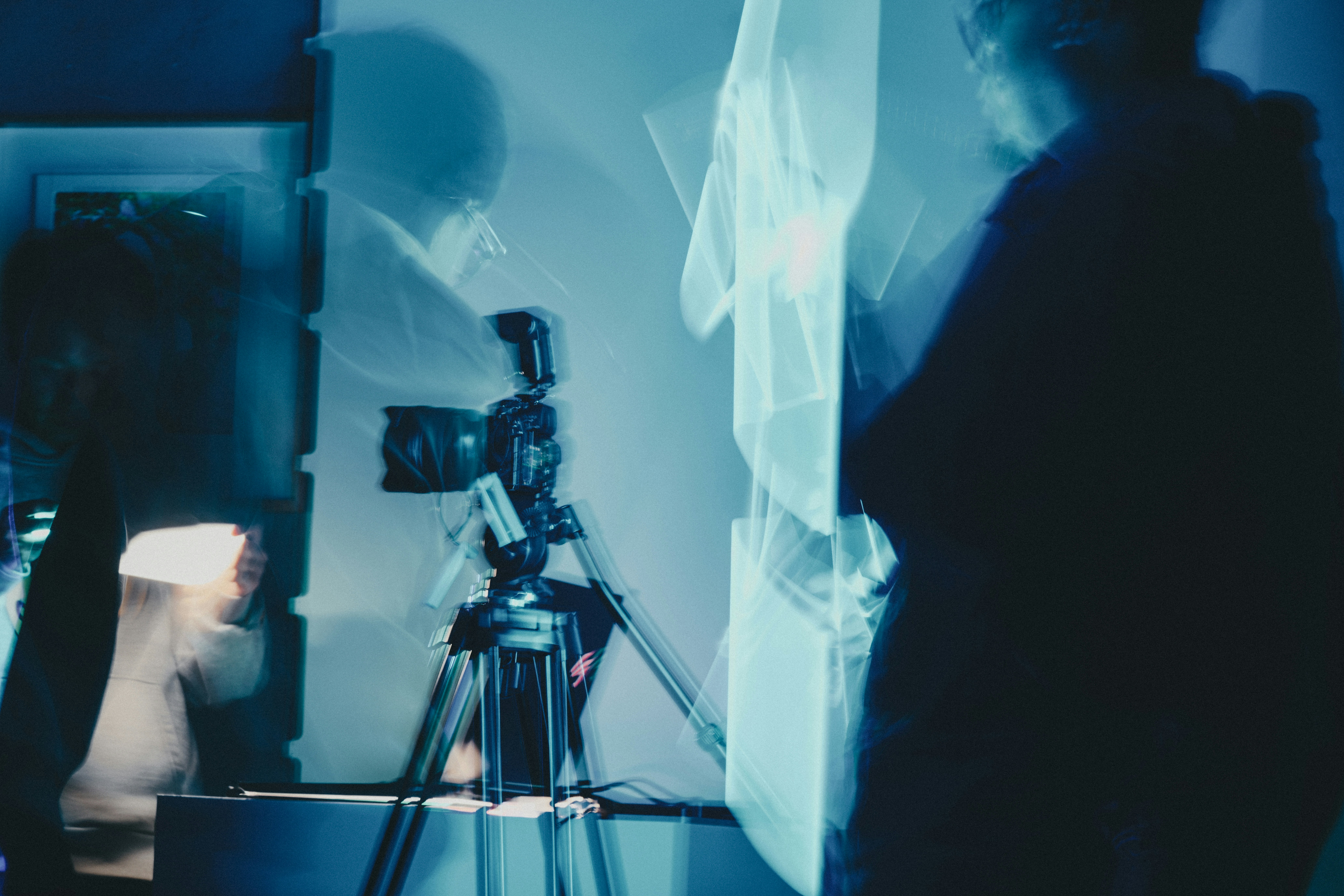 A camera on a tripod in a room with blue motion blur and light trails