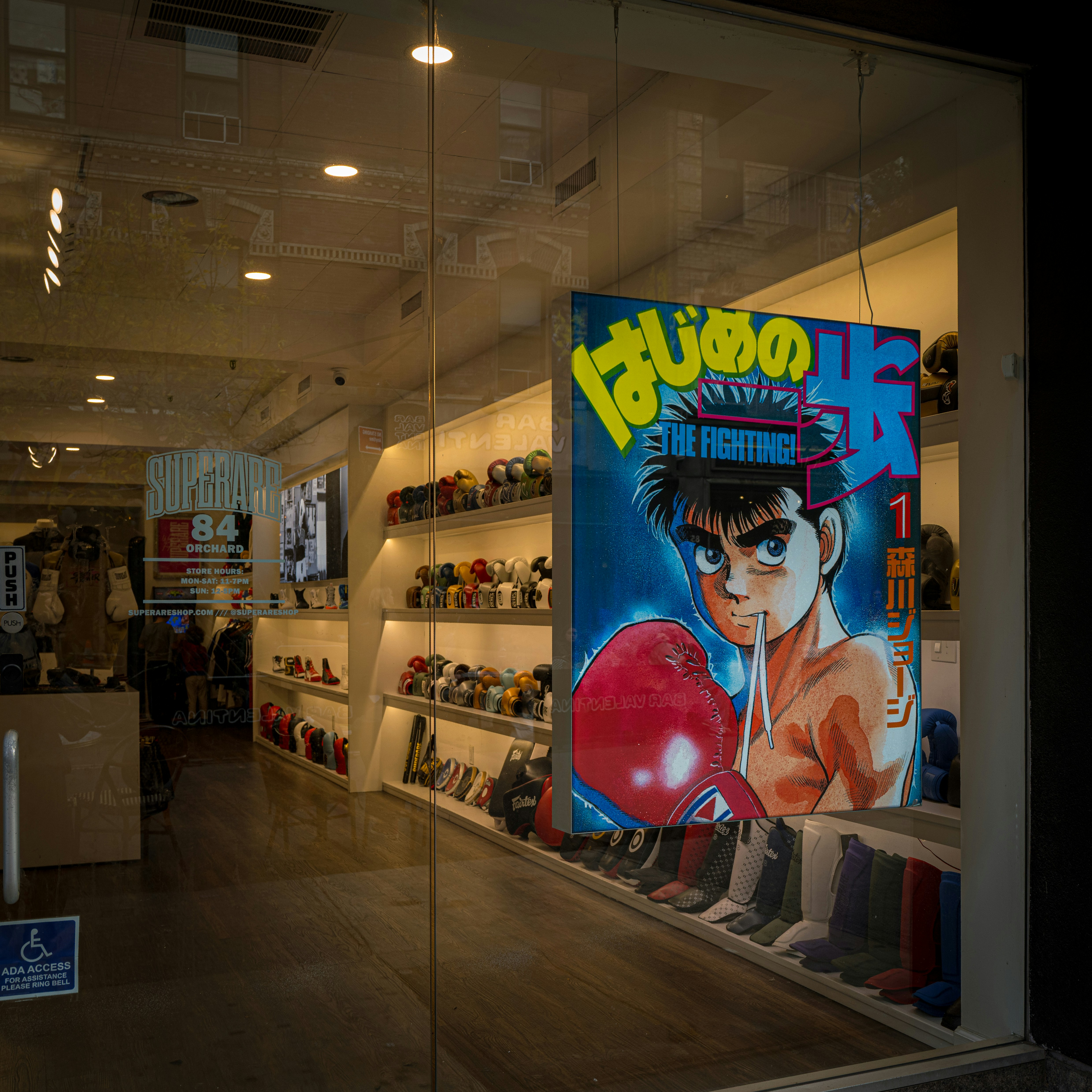 A storefront window displaying a large poster of a manga boxer beside shelves of boxing gloves