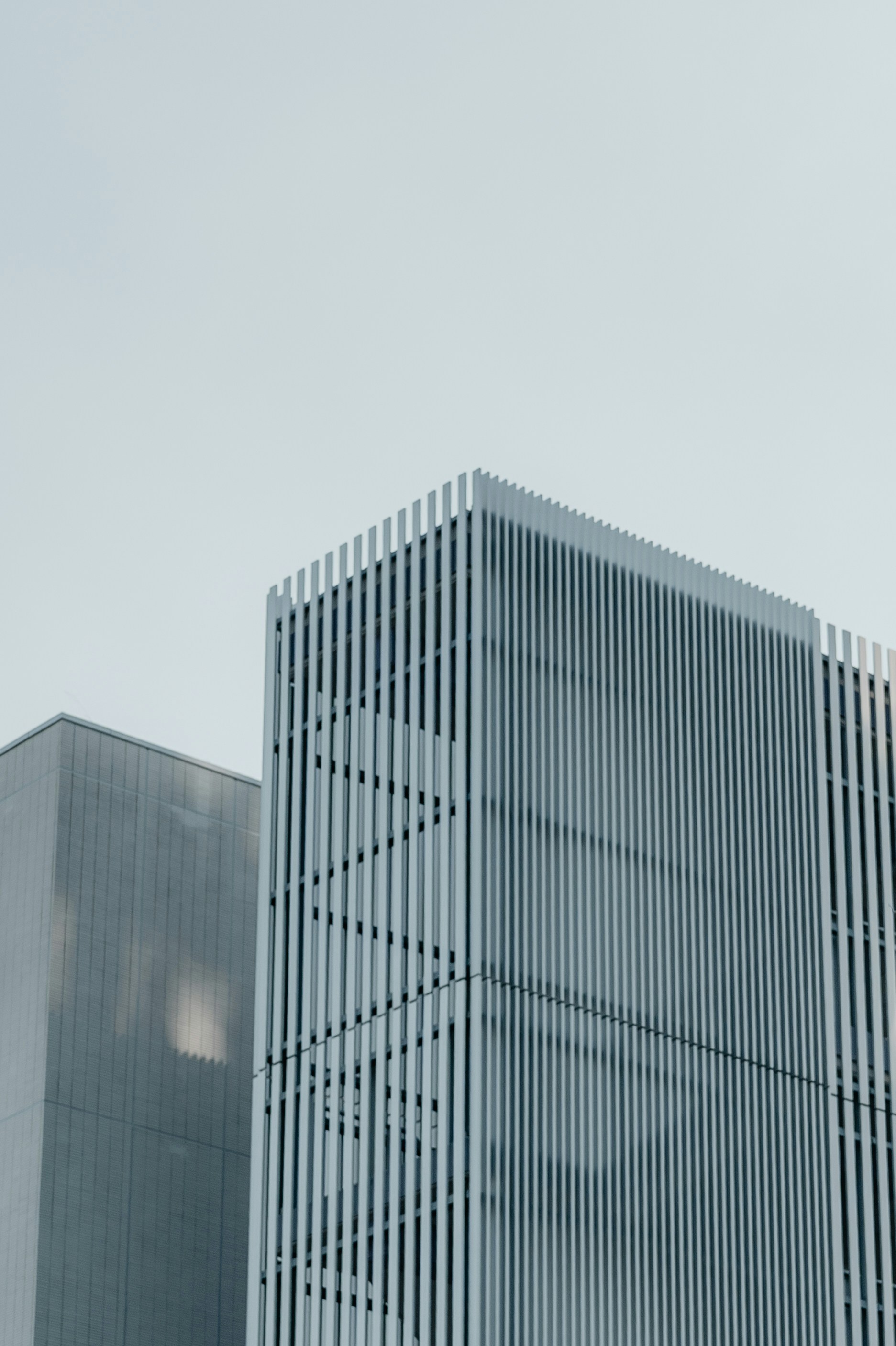 Modern office buildings with vertical louvers against a pale sky