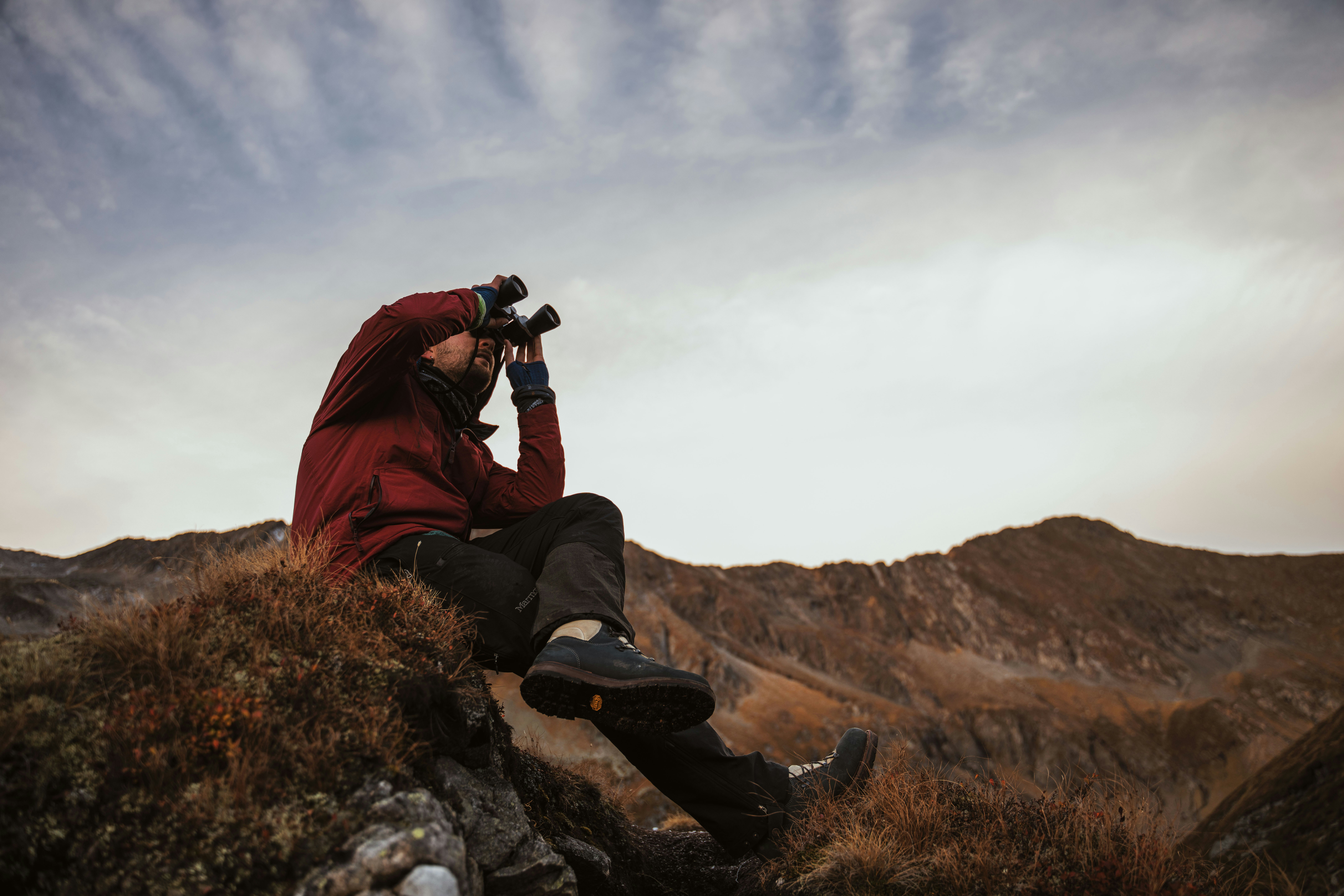Hiker using binoculars on a rocky mountain ridge
