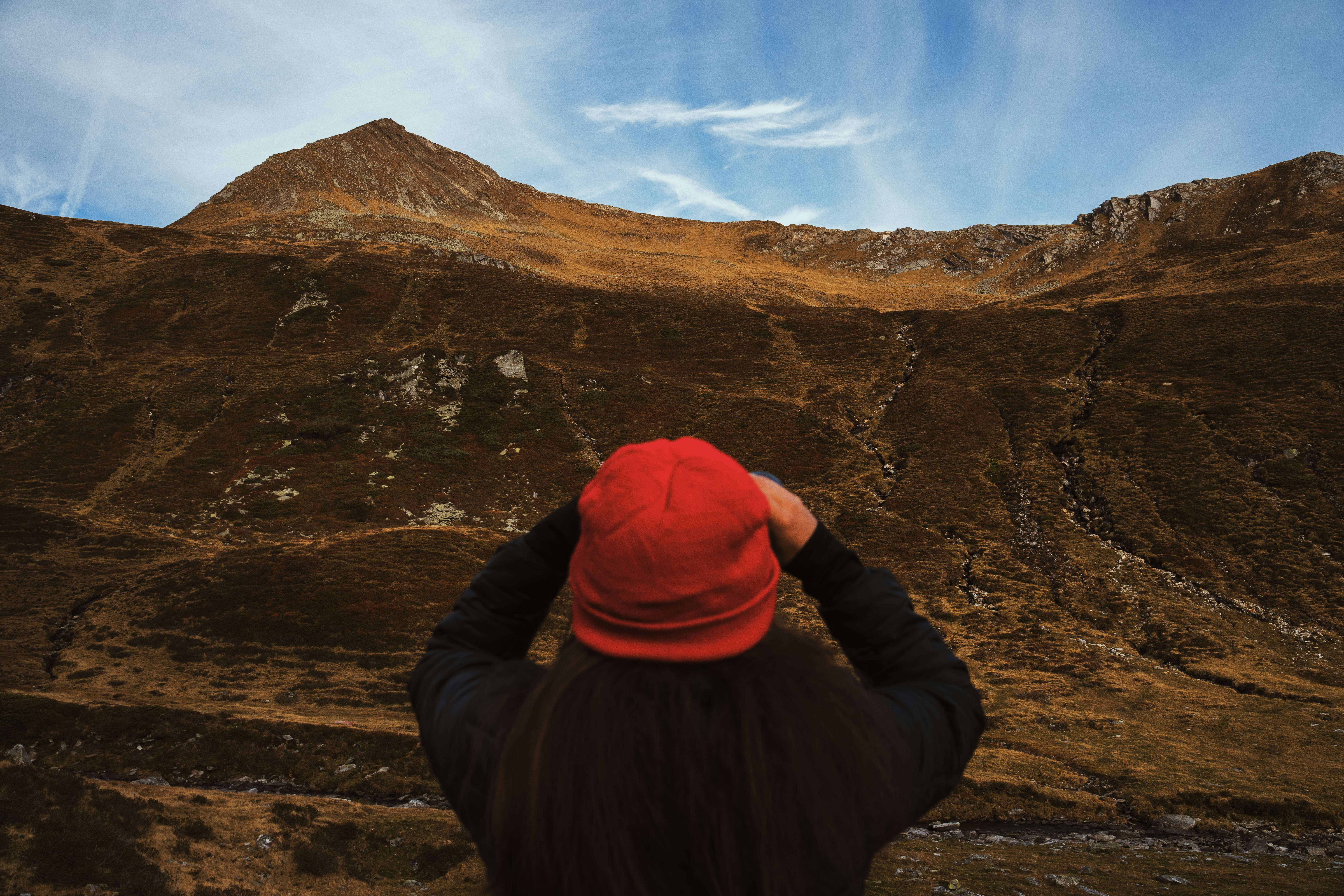 A person in a red beanie looking at a brown mountain landscape