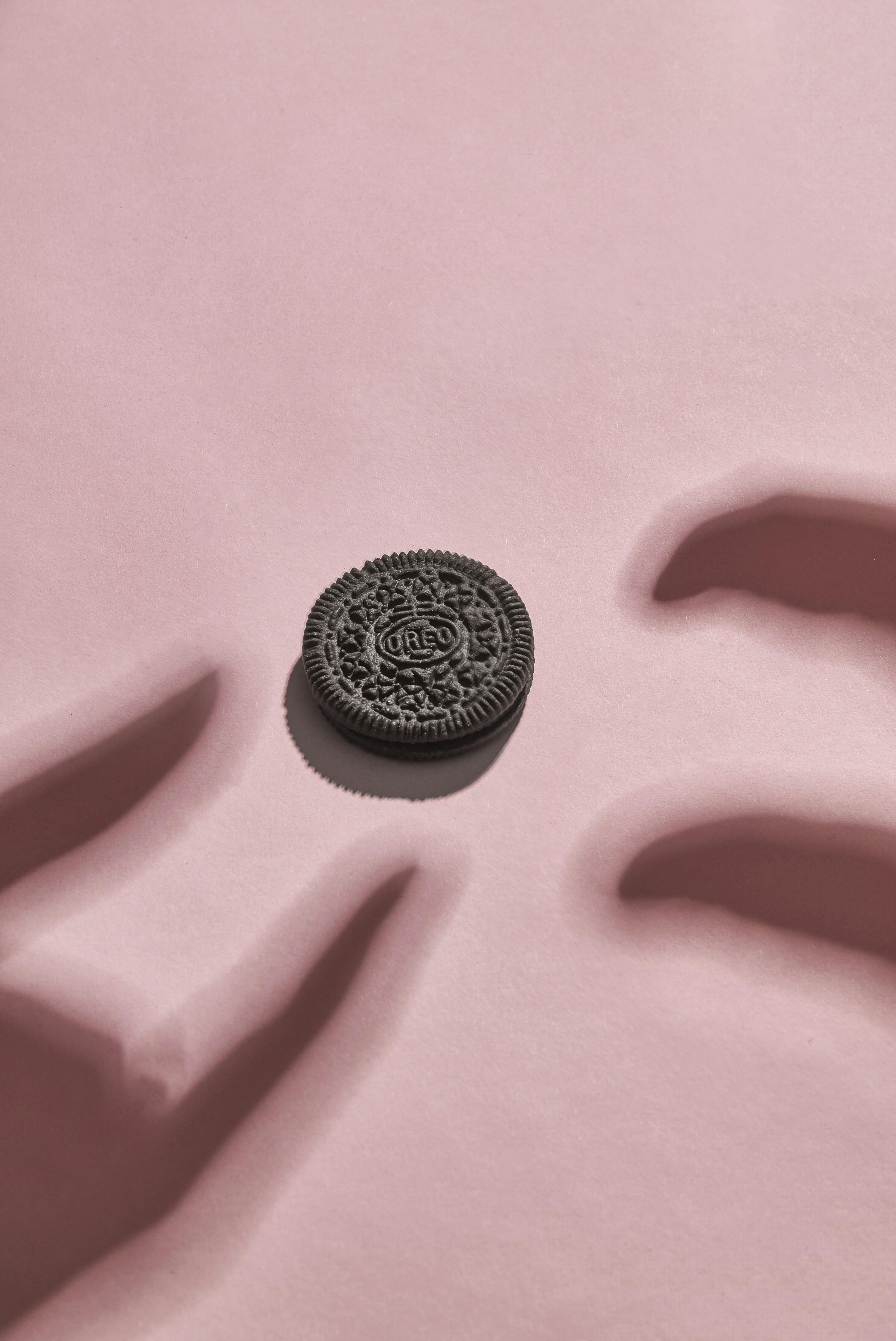 Chocolate sandwich cookie on pink surface - Free Photo on Unsplash