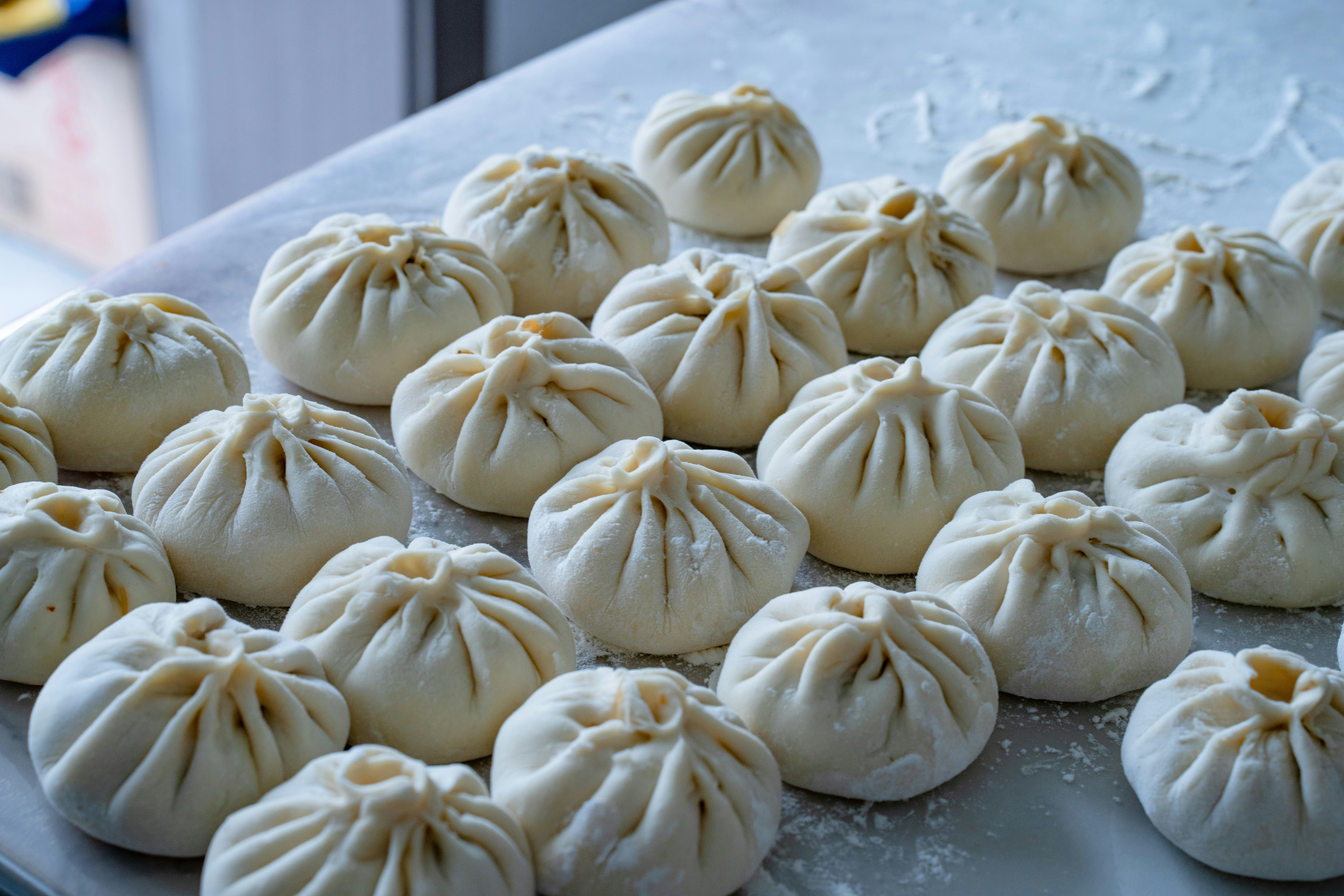 Many raw baozi dumplings arranged on a floured surface