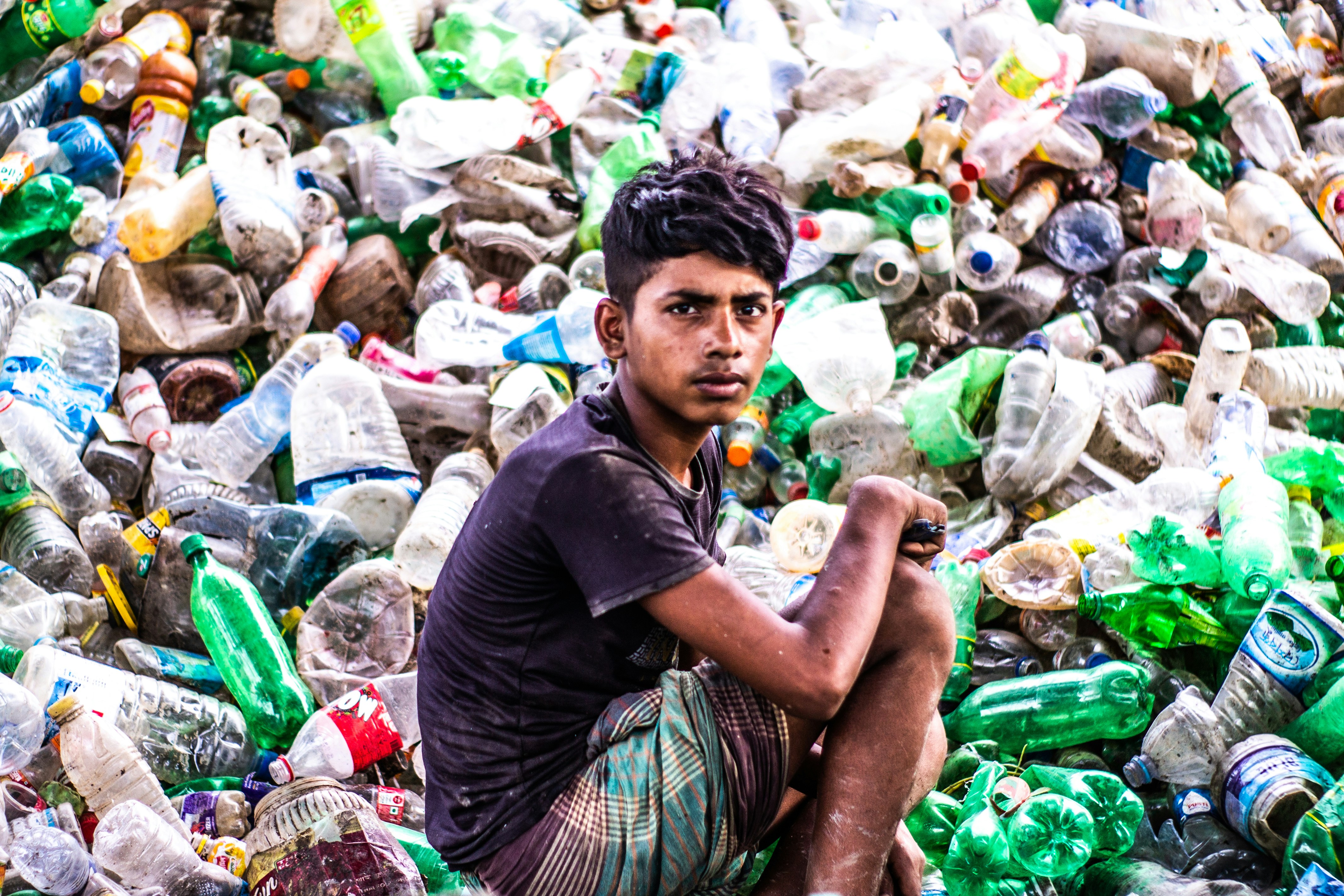 Young person sitting in plastic waste - Free Photo on Unsplash