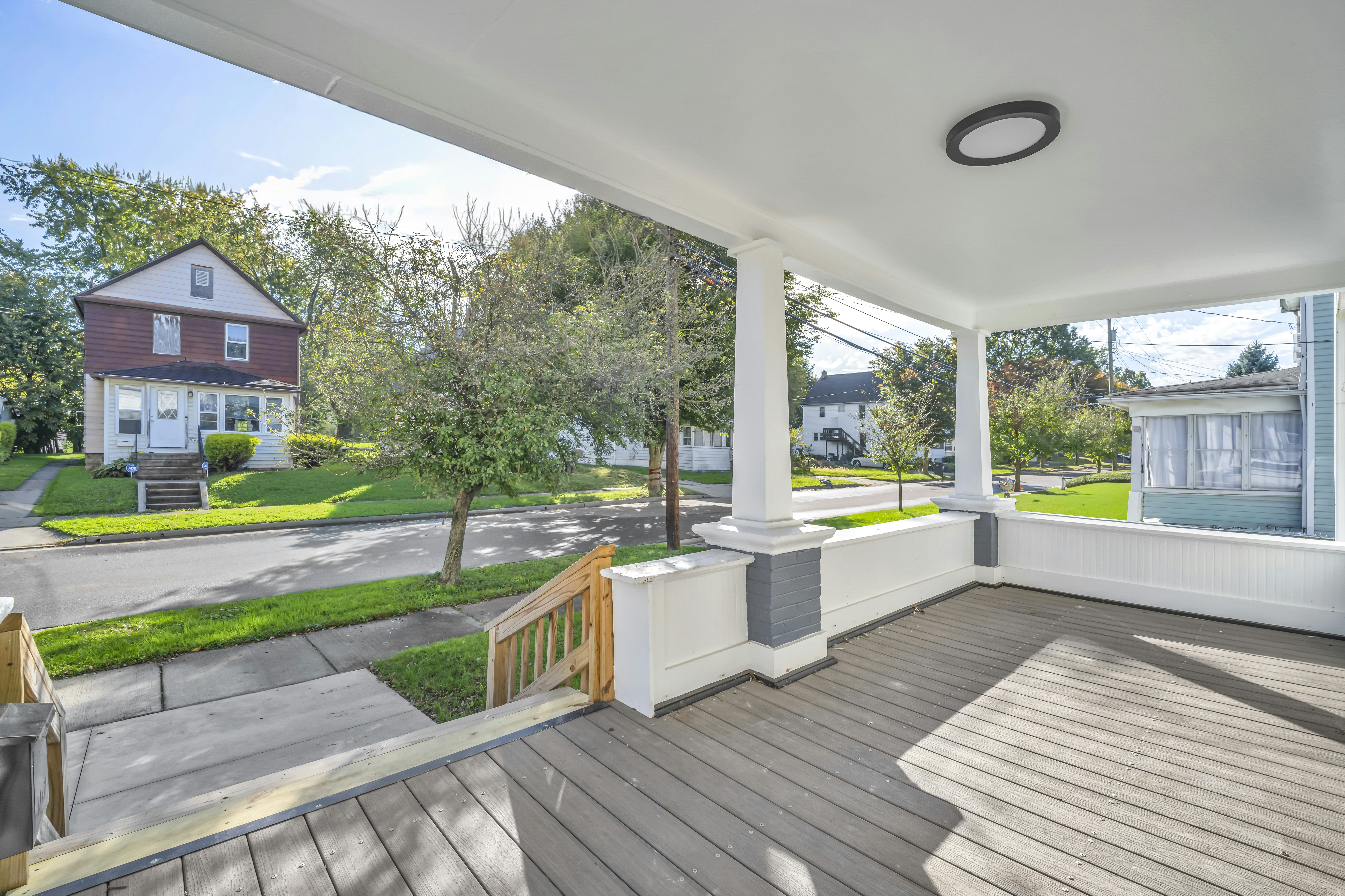 A view from a covered porch looking out onto a quiet residential street with houses