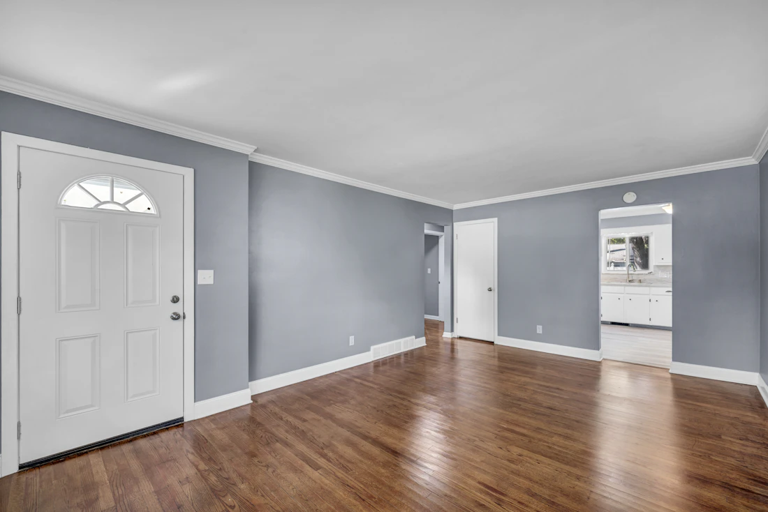 Freshly painted living room with gray walls, hardwood floors and a white door