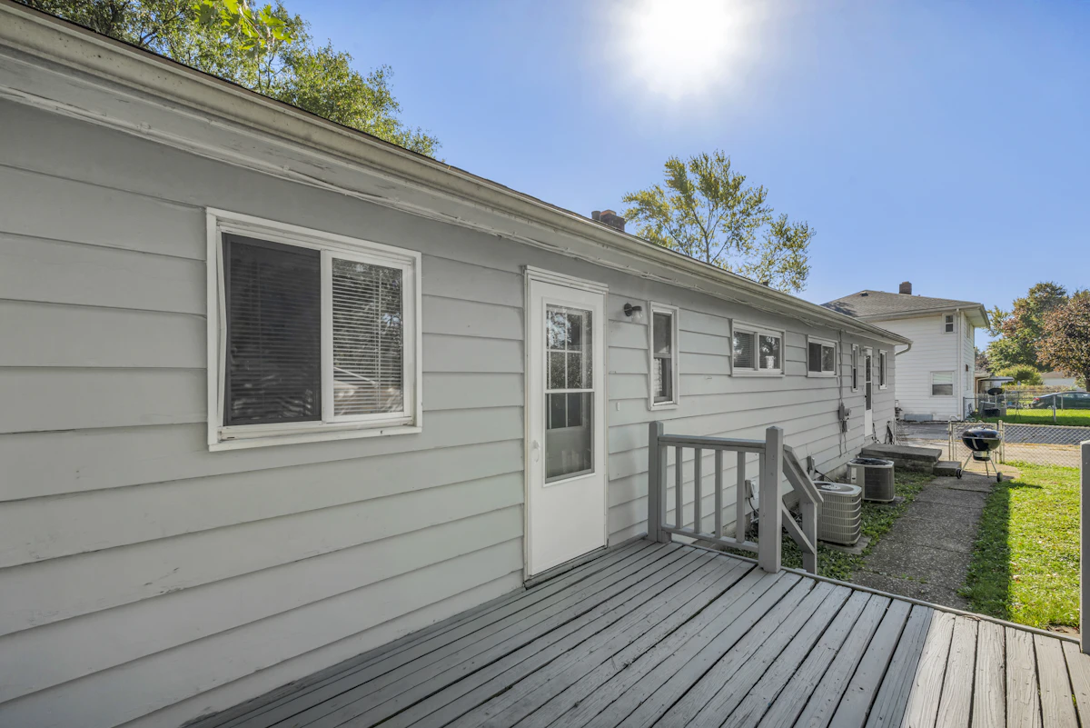 Wooden back deck attached to a house with gray siding