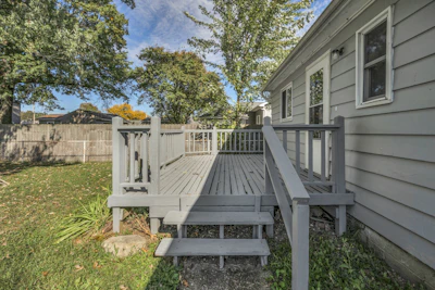 Gray painted wood deck with railings and steps off the back of a house