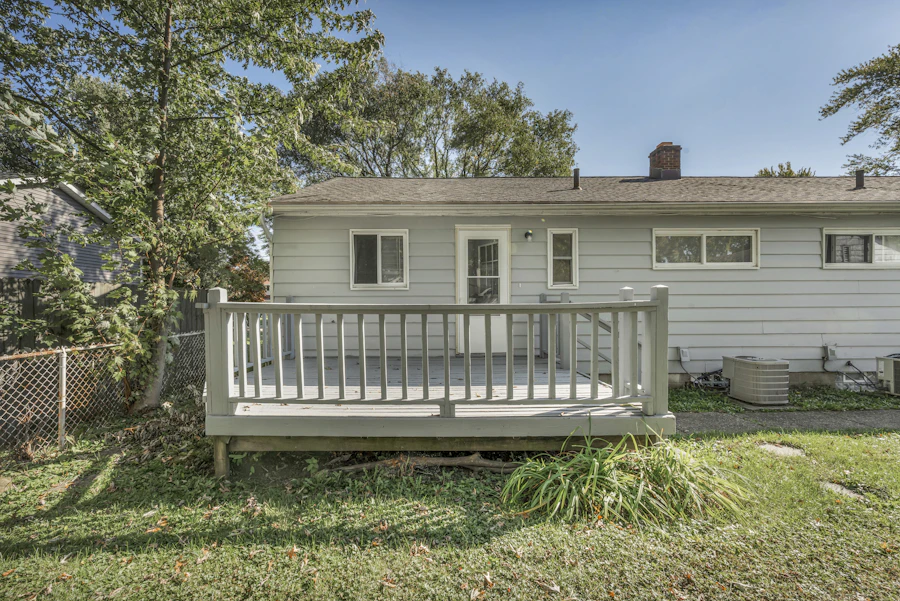 Painted wooden deck with railings at the back of a light grey house