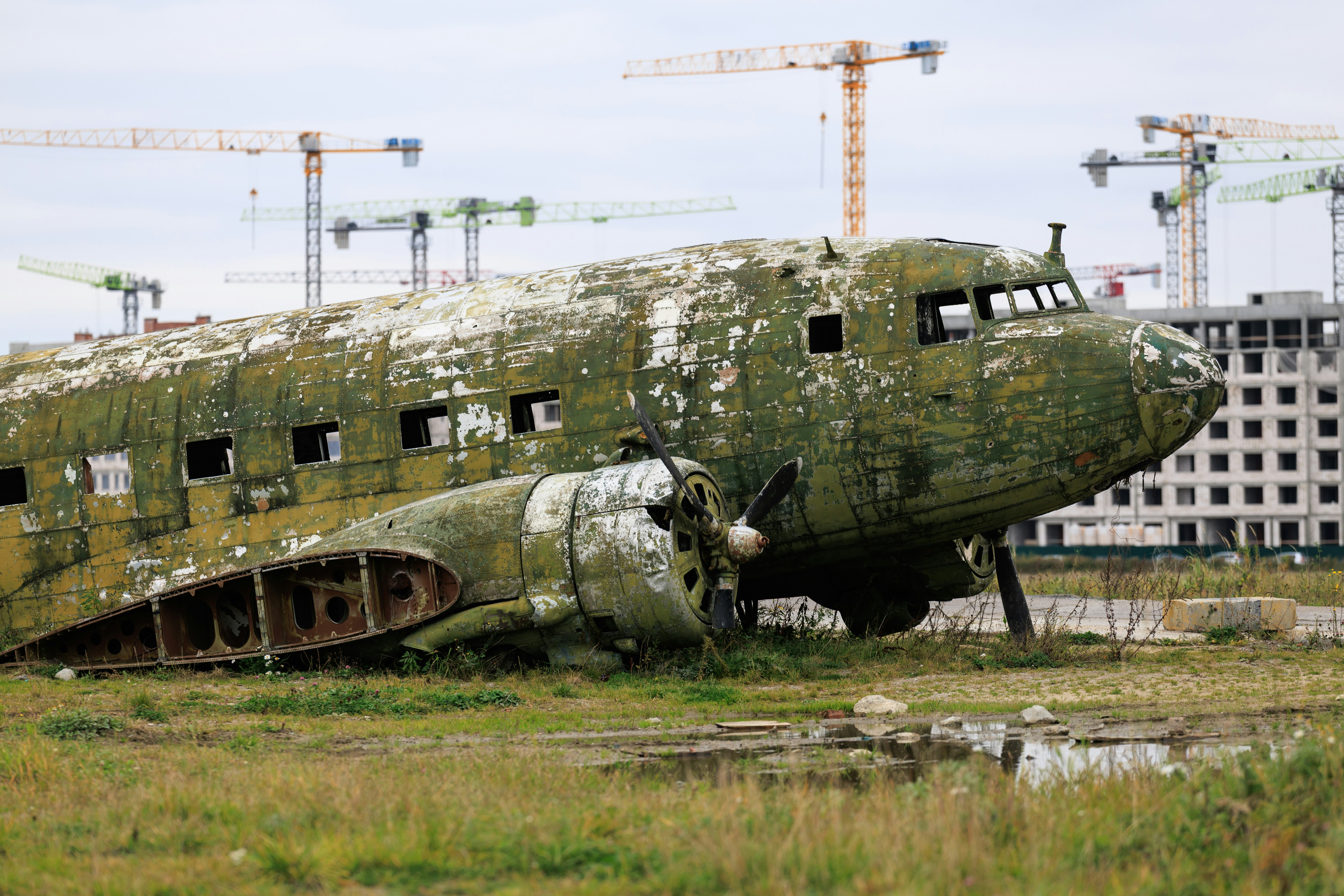 Abandoned airplane fuselage near construction cranes - Free Photo on ...