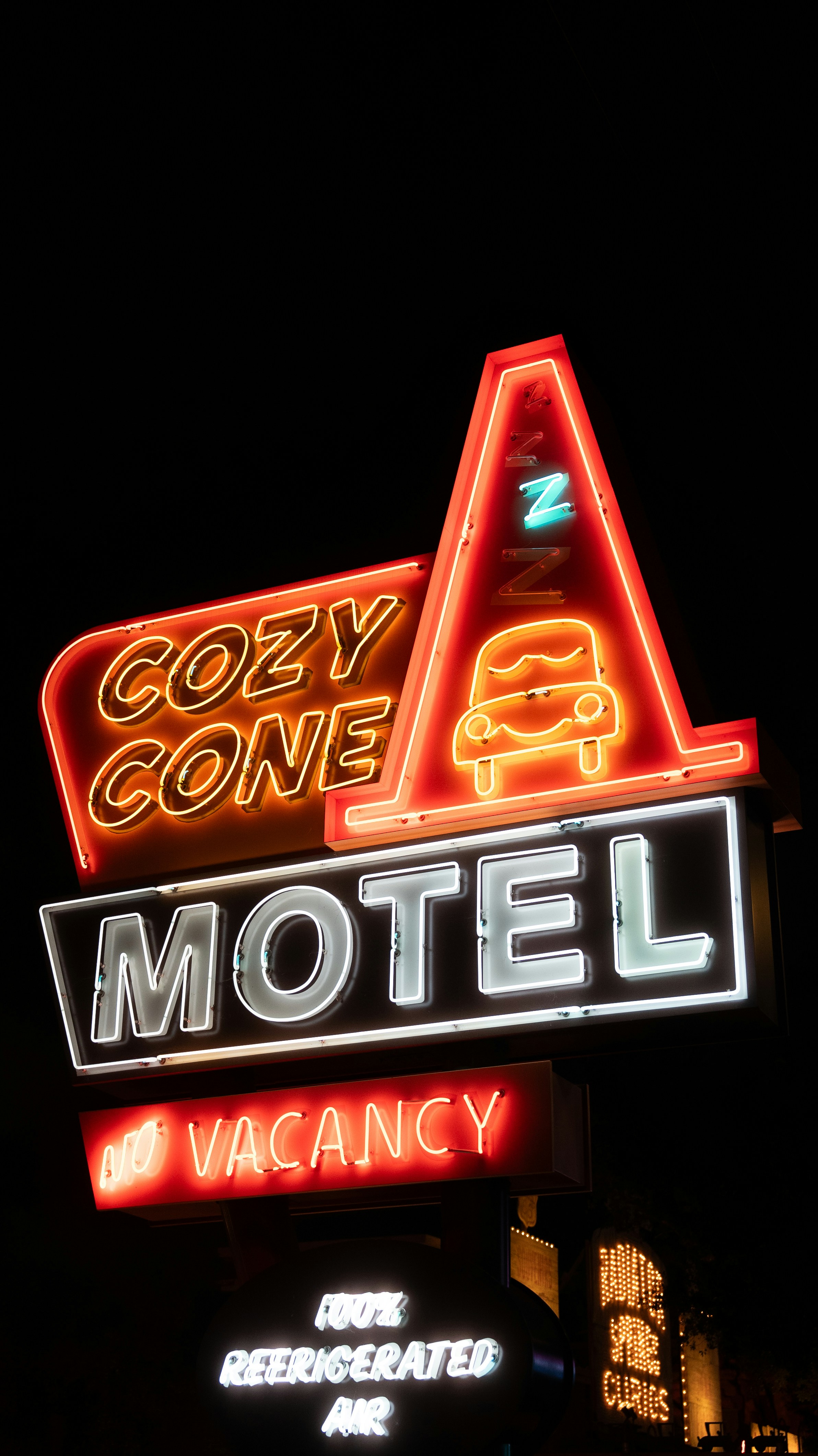 A neon sign reading Cozy Cone Motel with a no vacancy sign at night