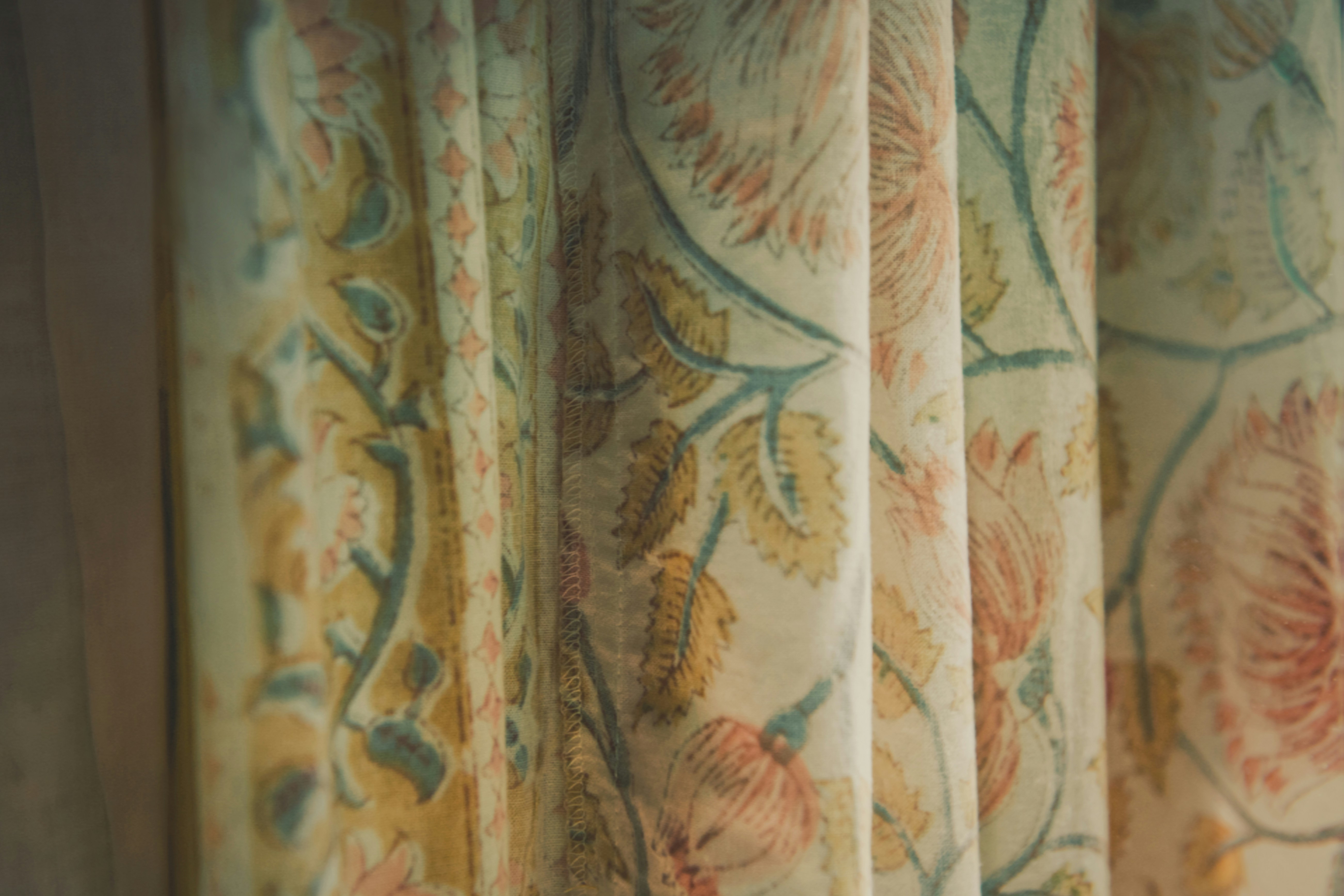Close-up of pleated fabric with a vintage floral pattern in muted yellow and blue tones