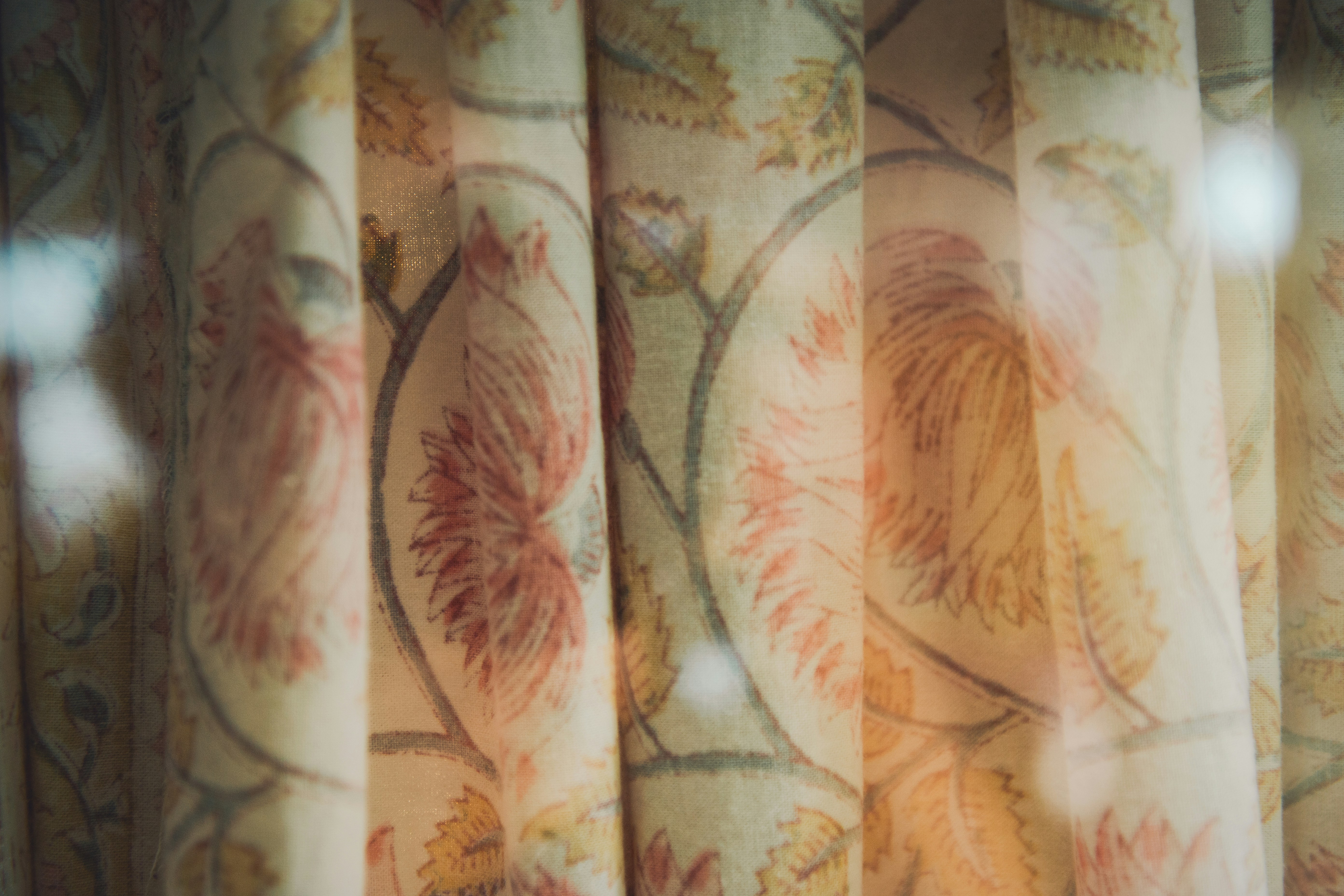 Close-up of pleated fabric with a vintage floral pattern in muted orange and green tones
