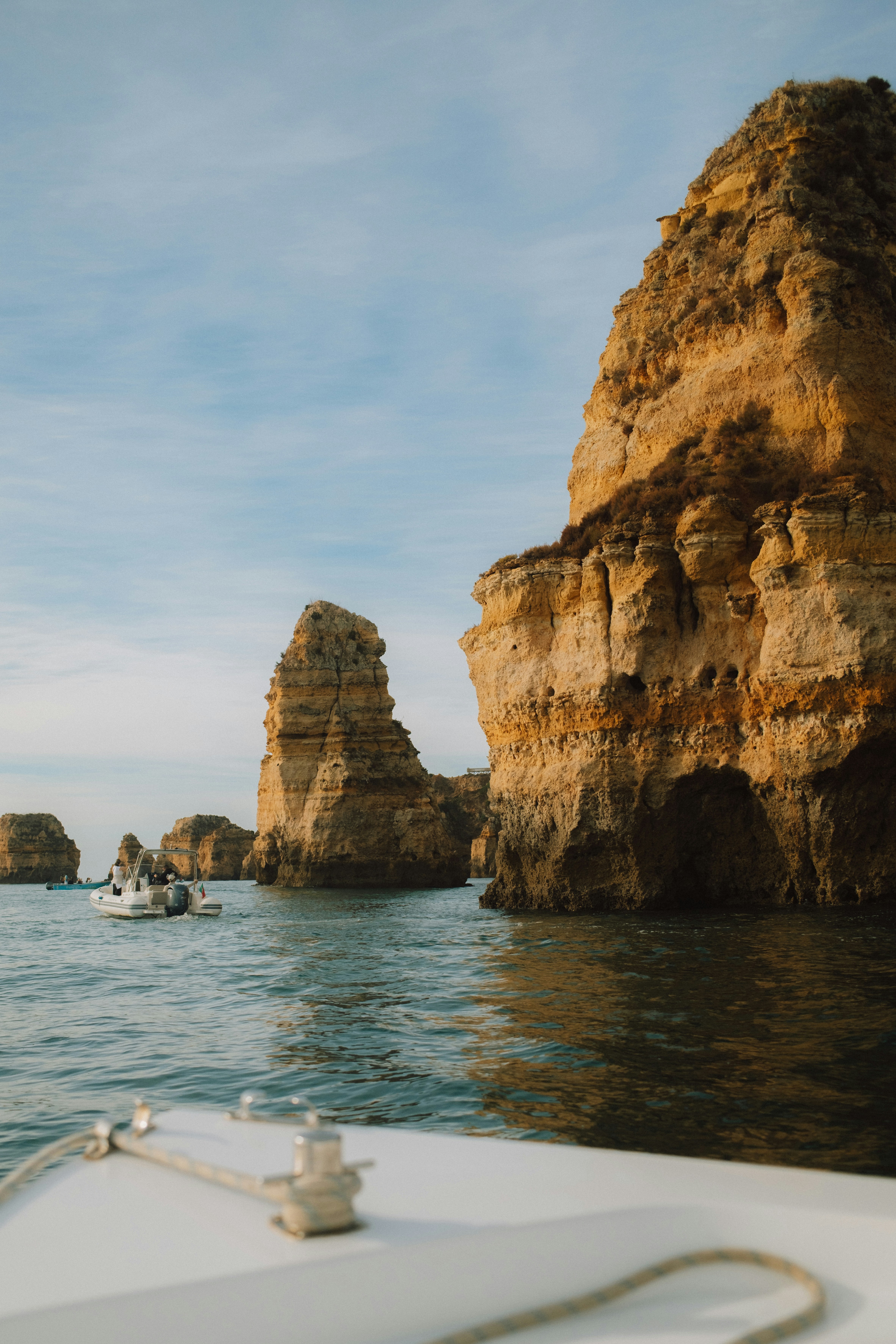A small motorboat cruising past towering golden limestone cliffs in the Algarve - 相关推荐