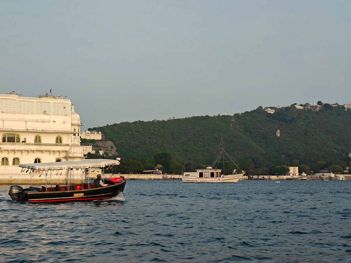 A boat passing a white palace on Lake Pichola