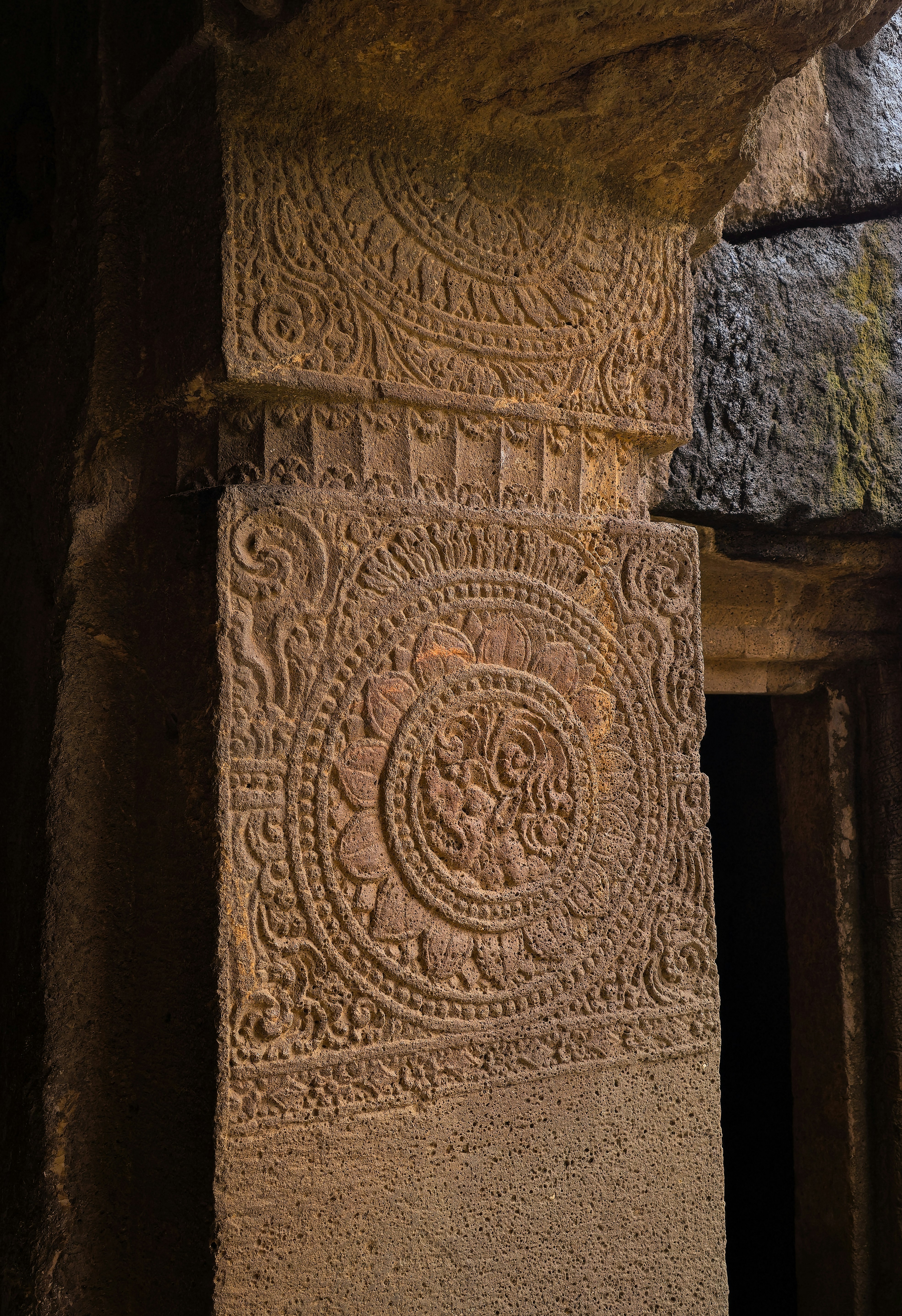 An intricately carved stone pillar with a circular floral medallion in the Ajanta Caves, Maharashtra