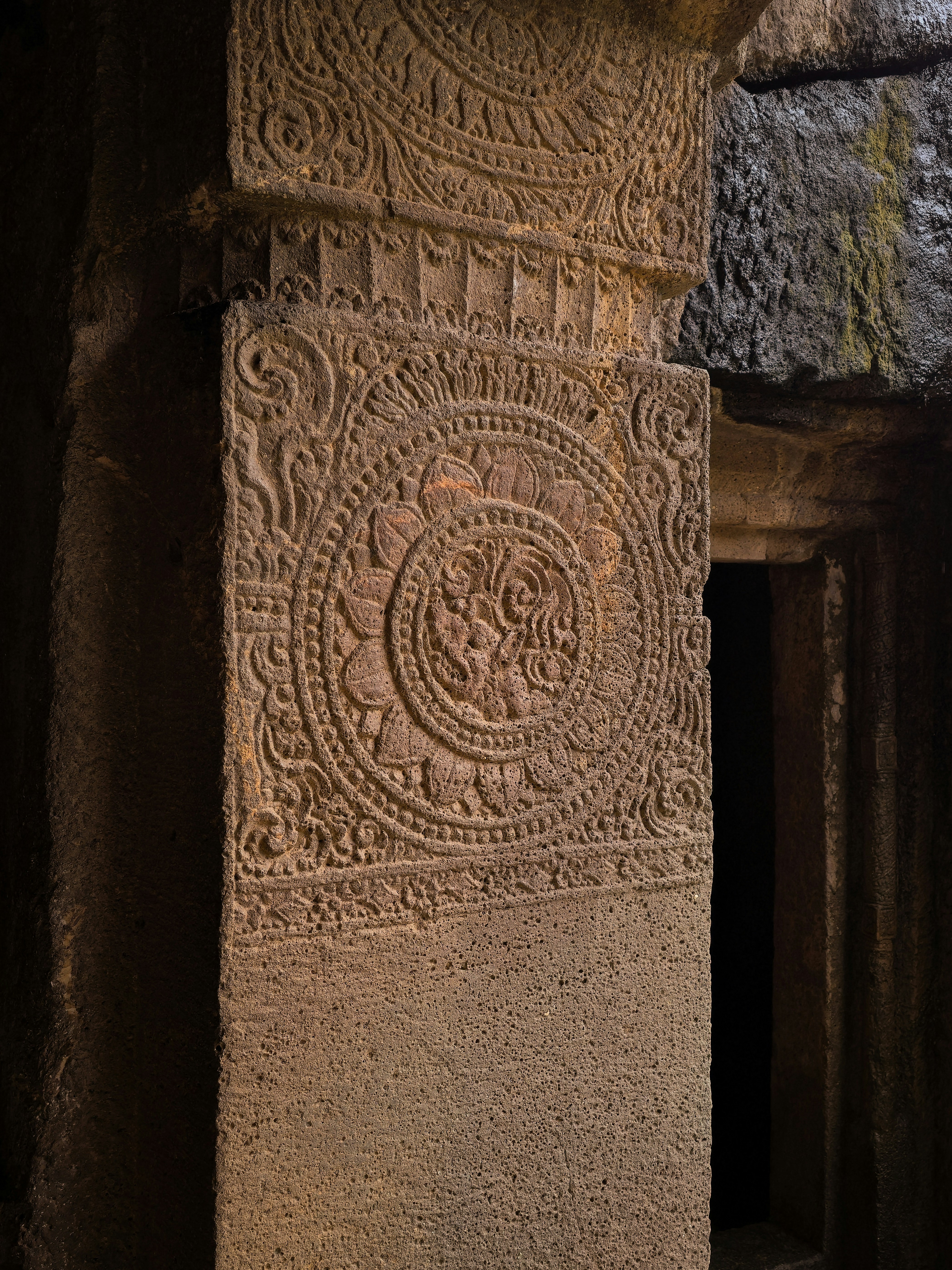 An intricately carved stone pillar with a circular floral medallion at the Ajanta Caves in India