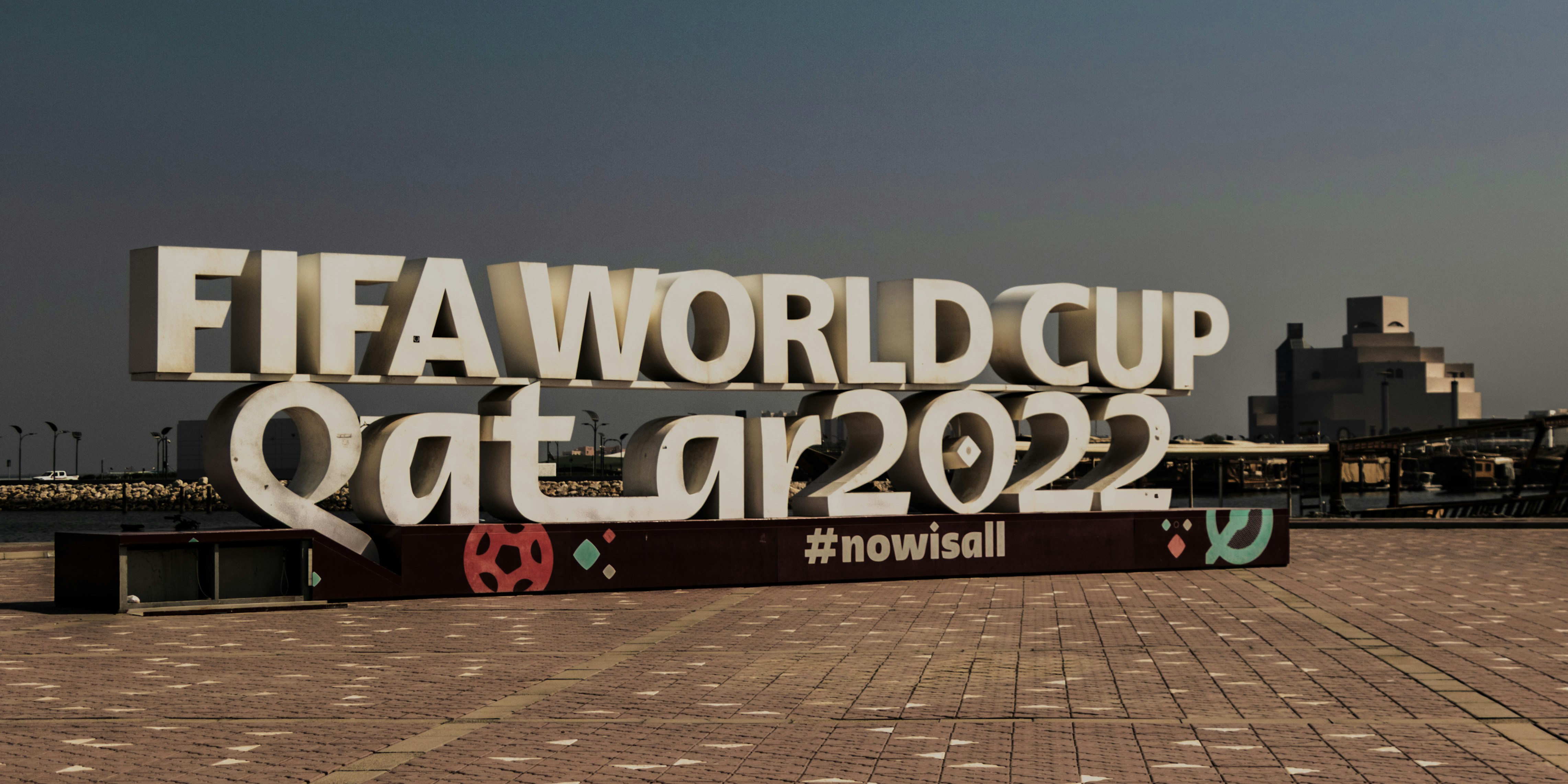 Large white FIFA World Cup Qatar 2022 sign on a paved waterfront promenade