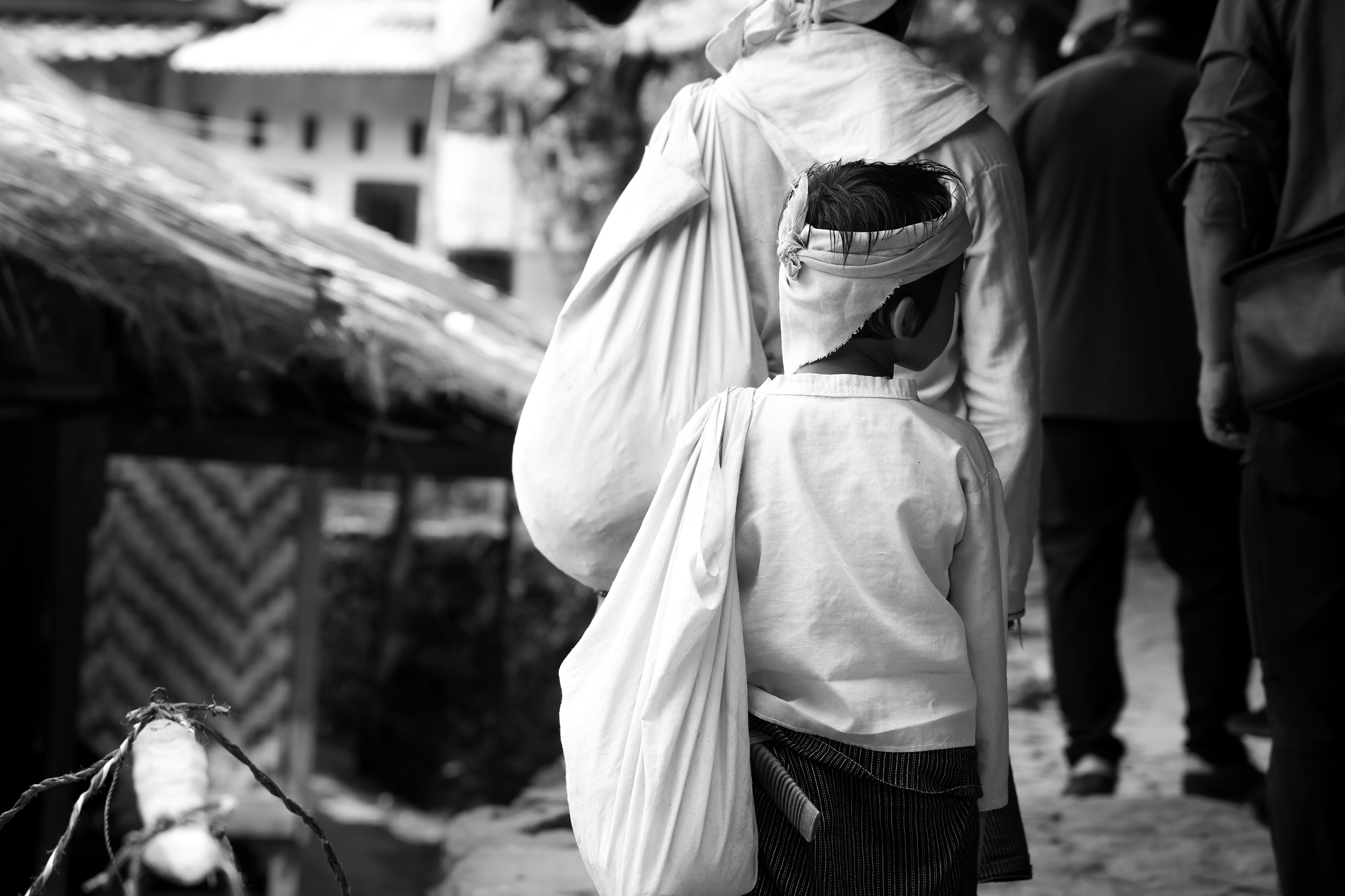 A child and an adult walking along a path carrying large white cloth bags