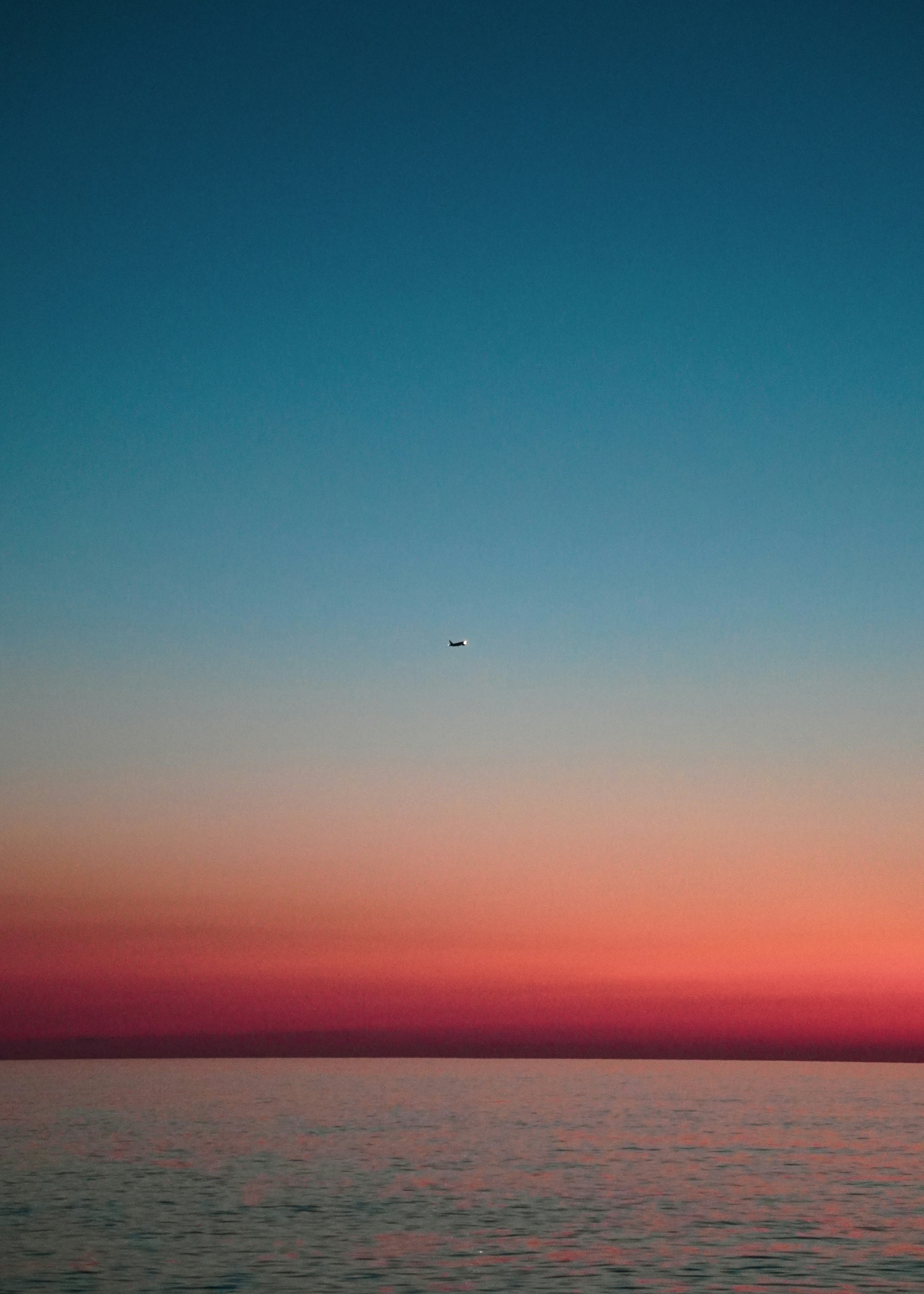 Airplane over calm sea at dusk - Free Photo on Unsplash