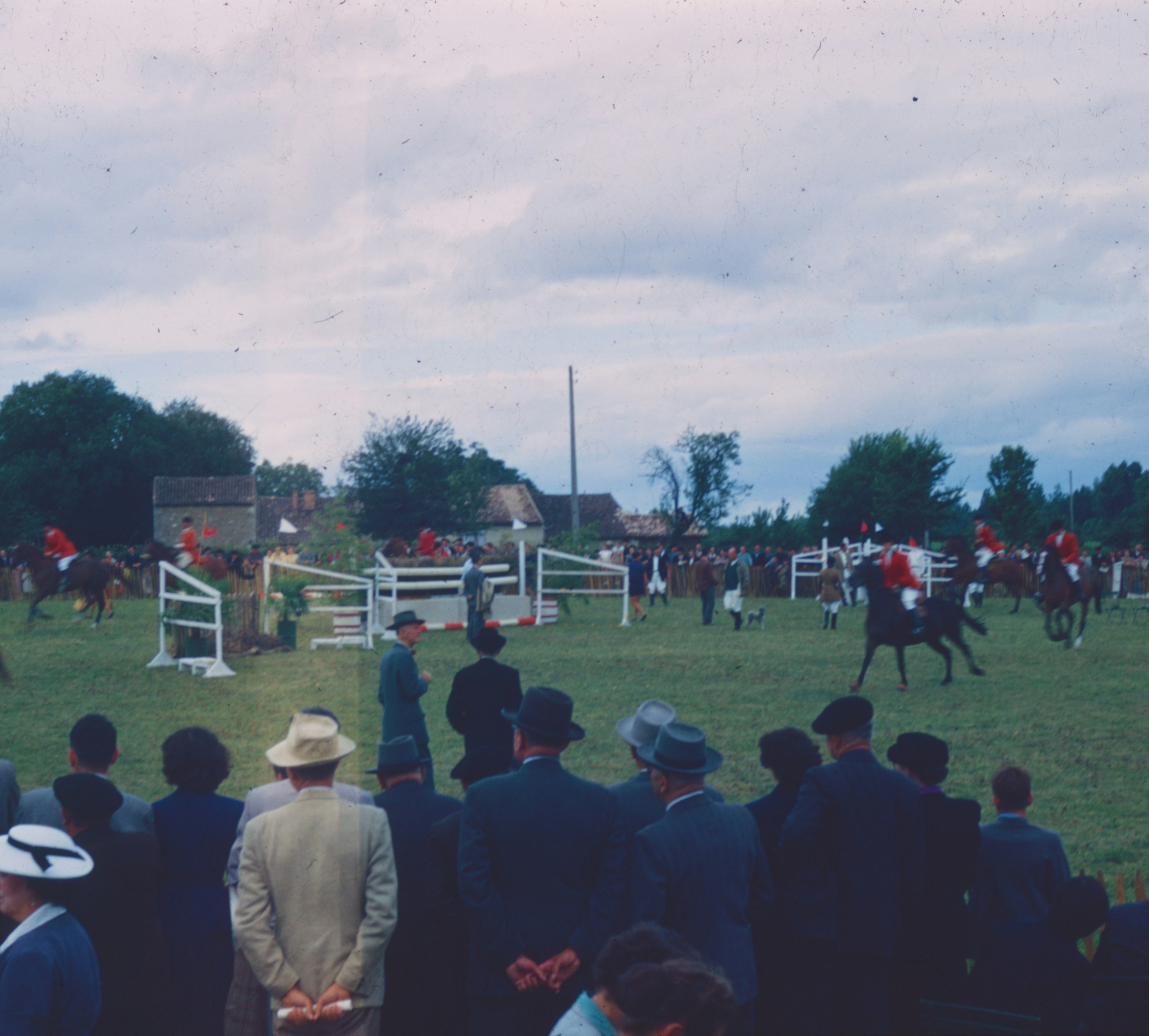 A crowd of people watching riders on horses during an equestrian show jumping event
