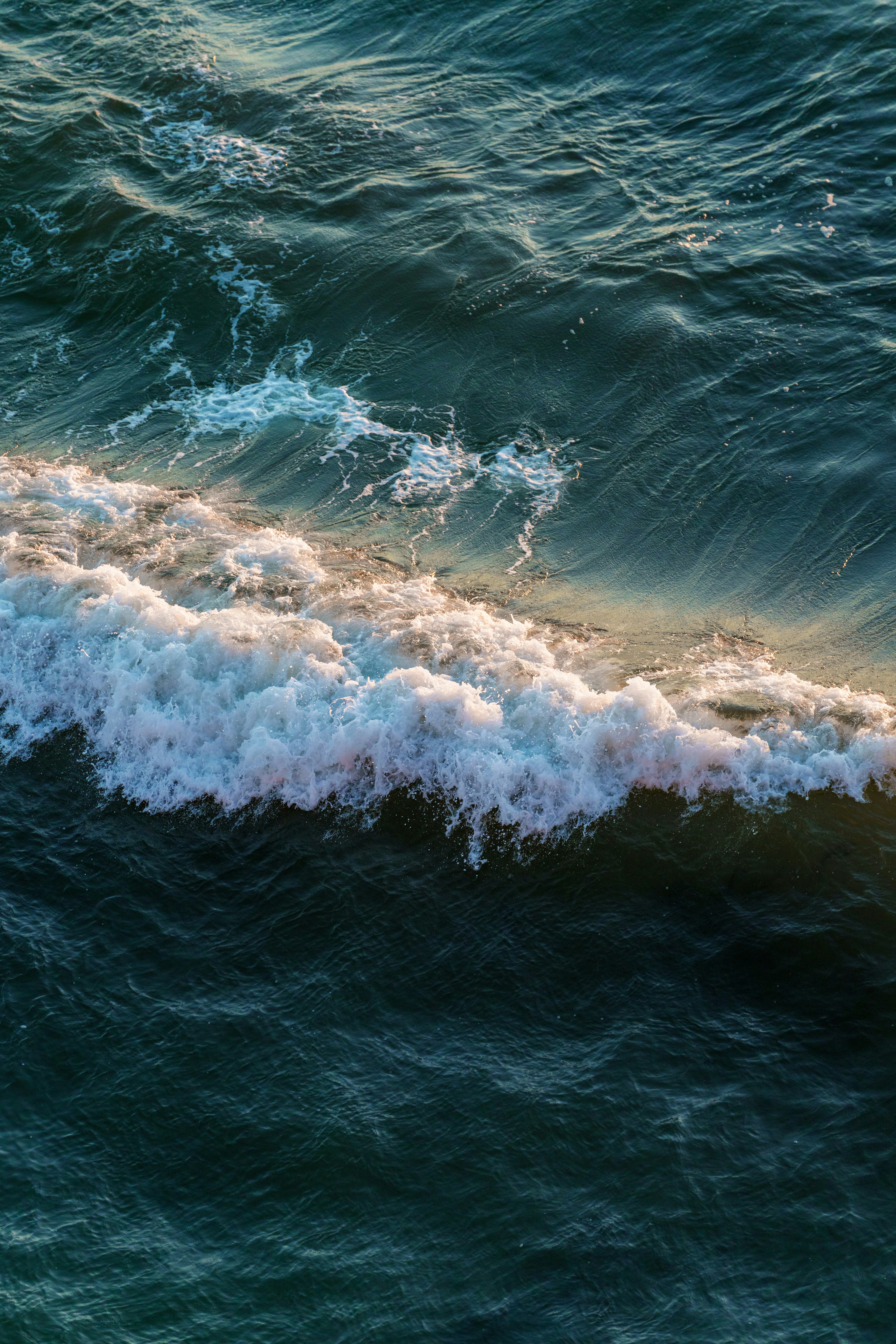 A breaking ocean wave with white foam and golden light on the crest - 相关推荐