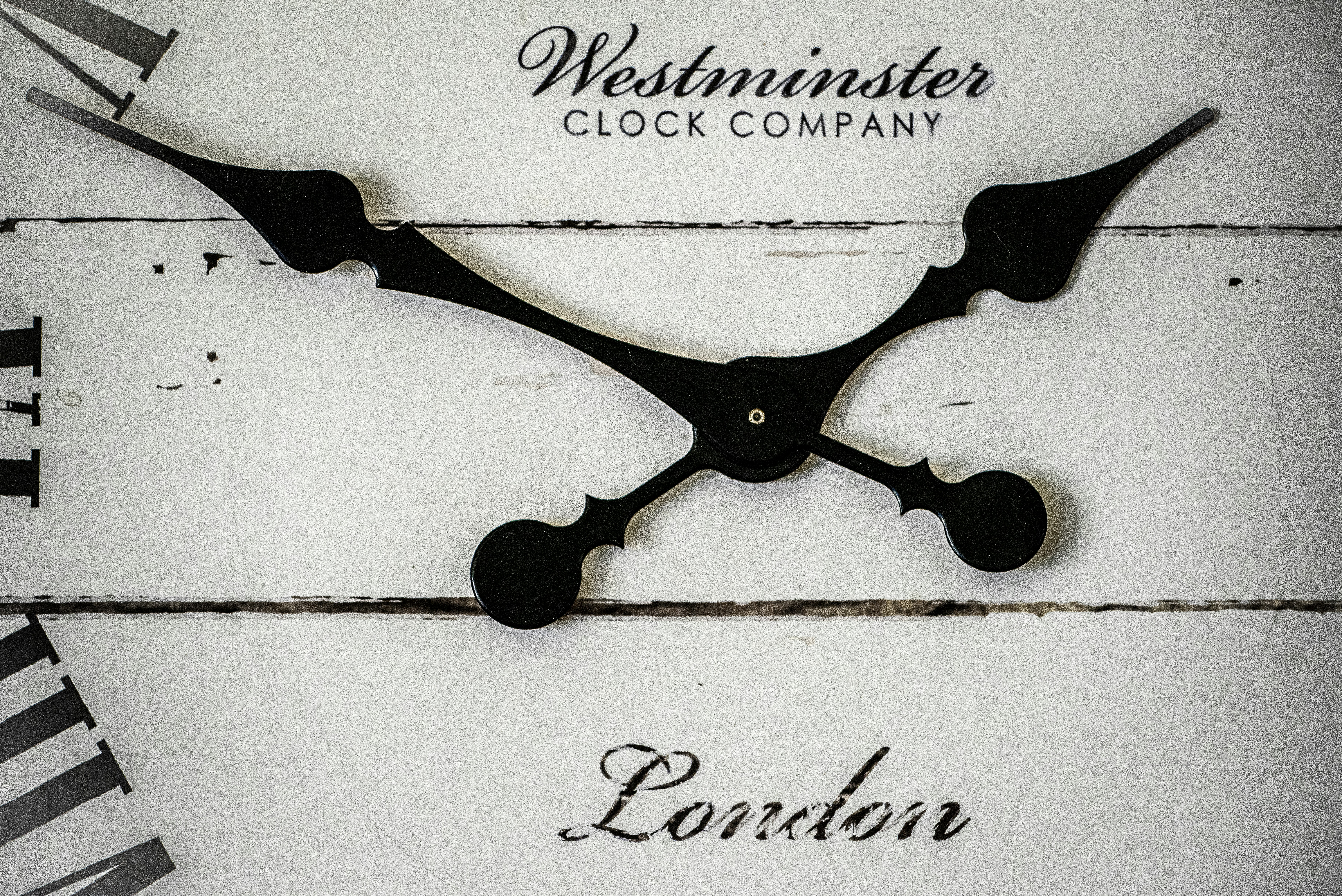 Close up of a white clock face with black hands and the text Westminster Clock Company London