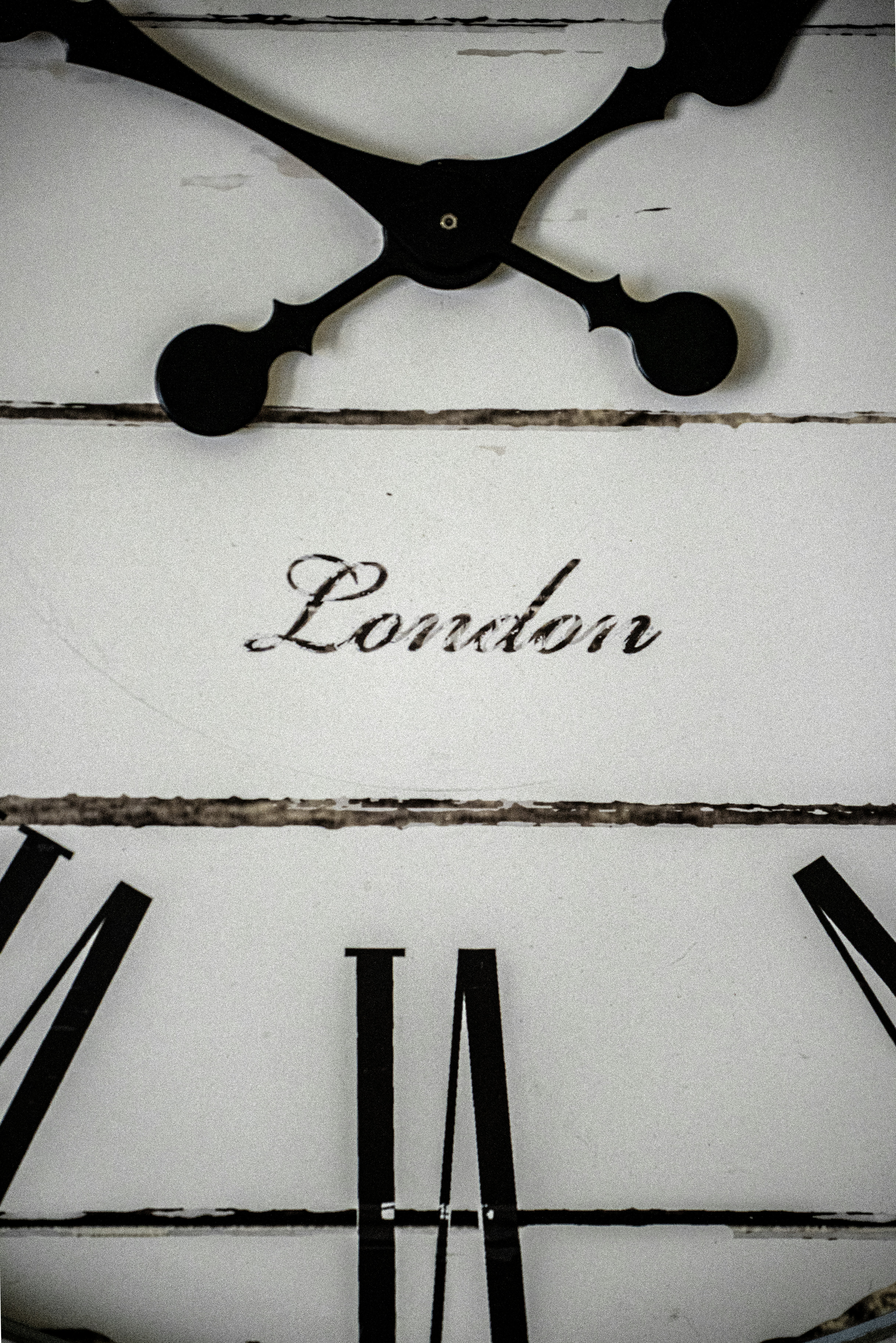 A close-up of a white wall clock face with black Roman numerals and the word London
