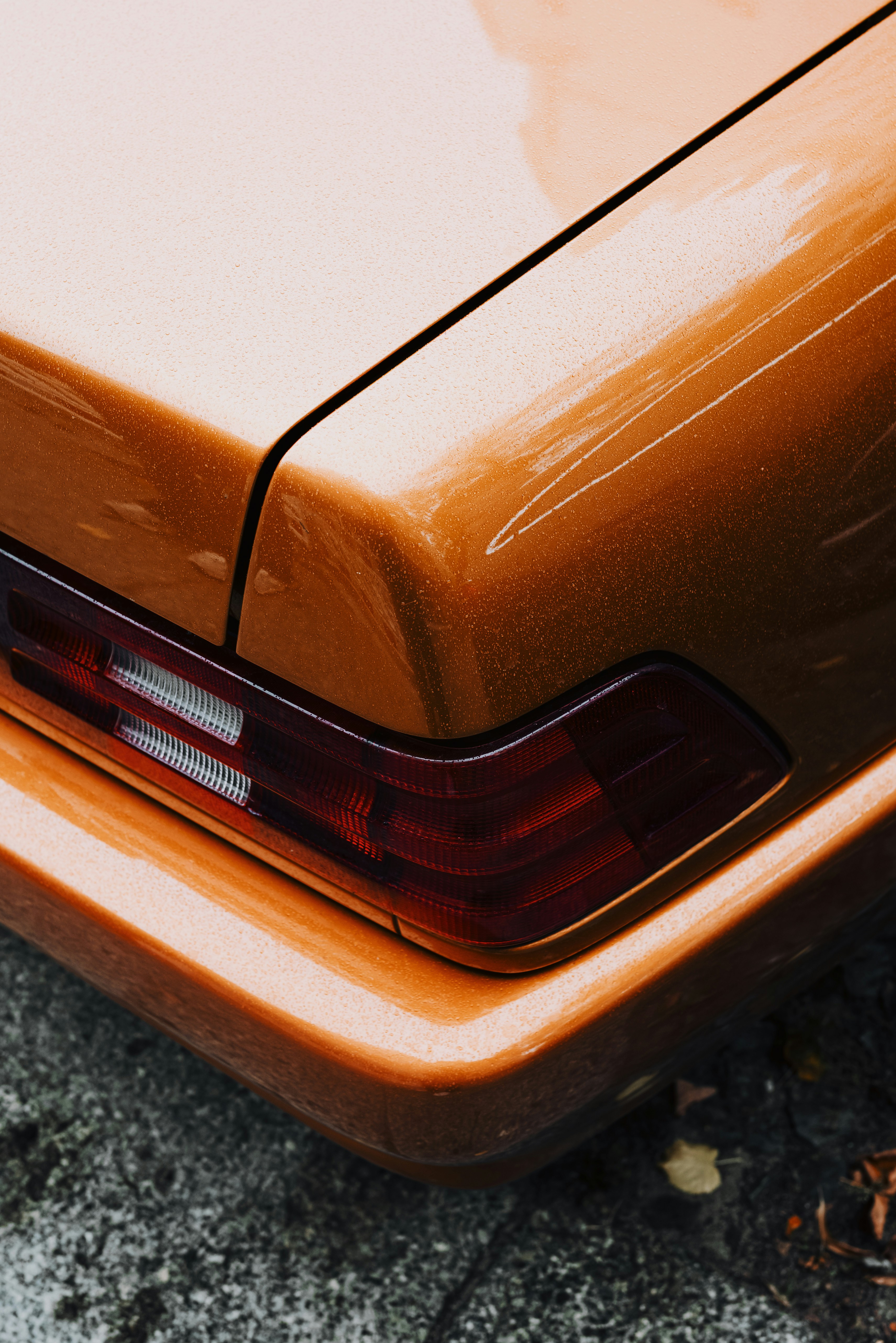 Close-up of the rear taillight and metallic orange paint on a vintage car