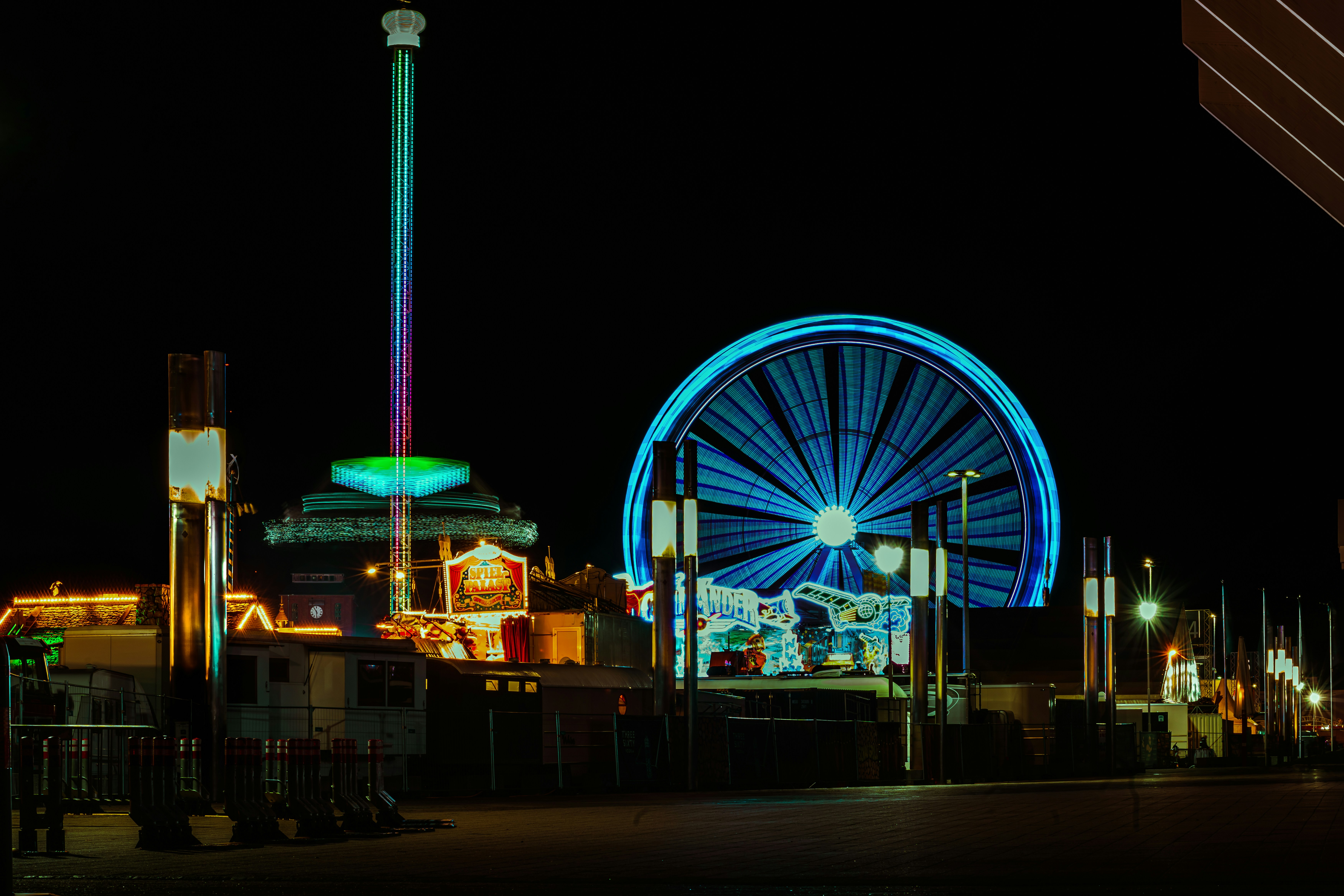 Glowing ferris wheel and drop tower ride illuminated at a night carnival