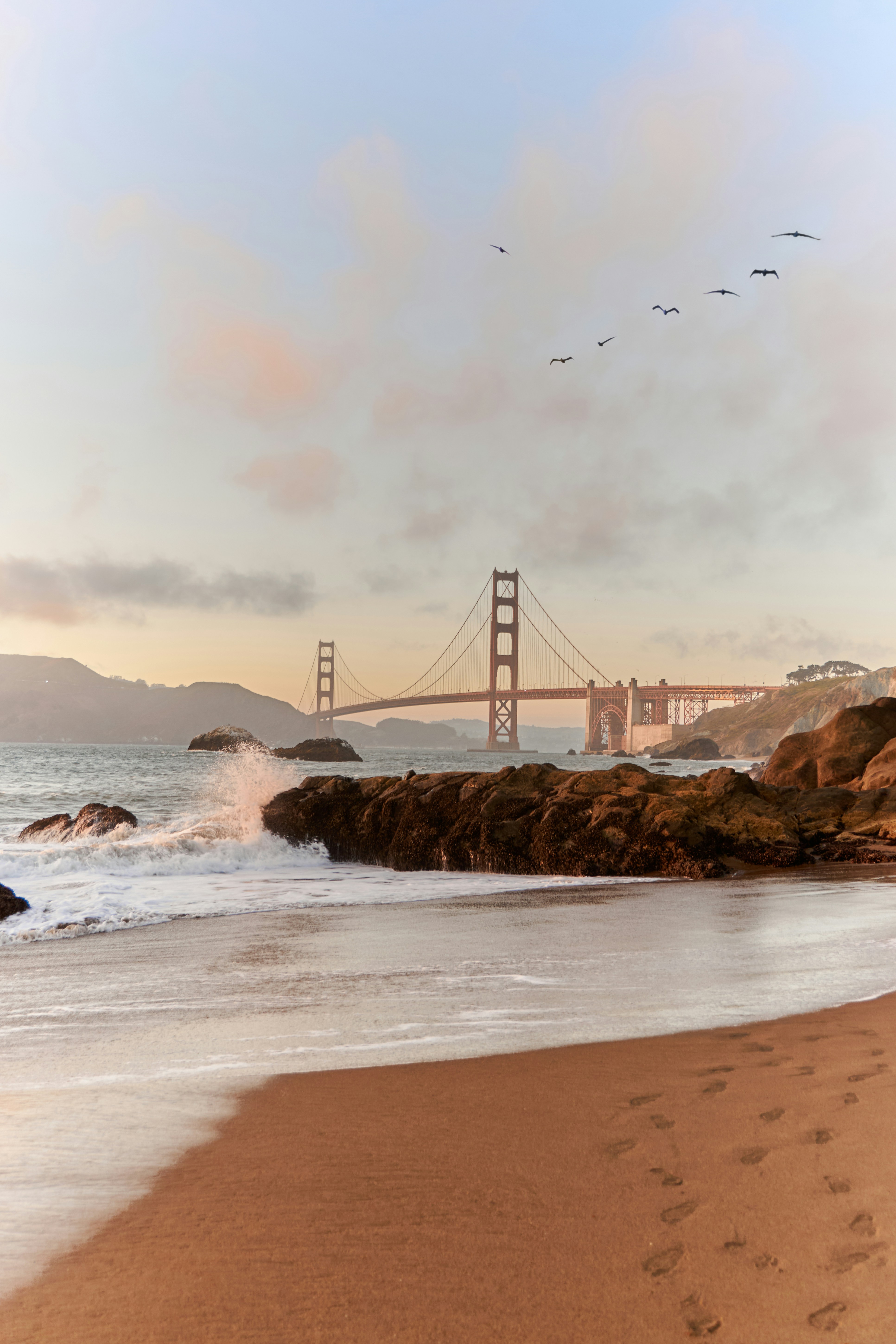 The Golden Gate Bridge in San Francisco at low sun with waves crashing on rocky shore - 相关推荐