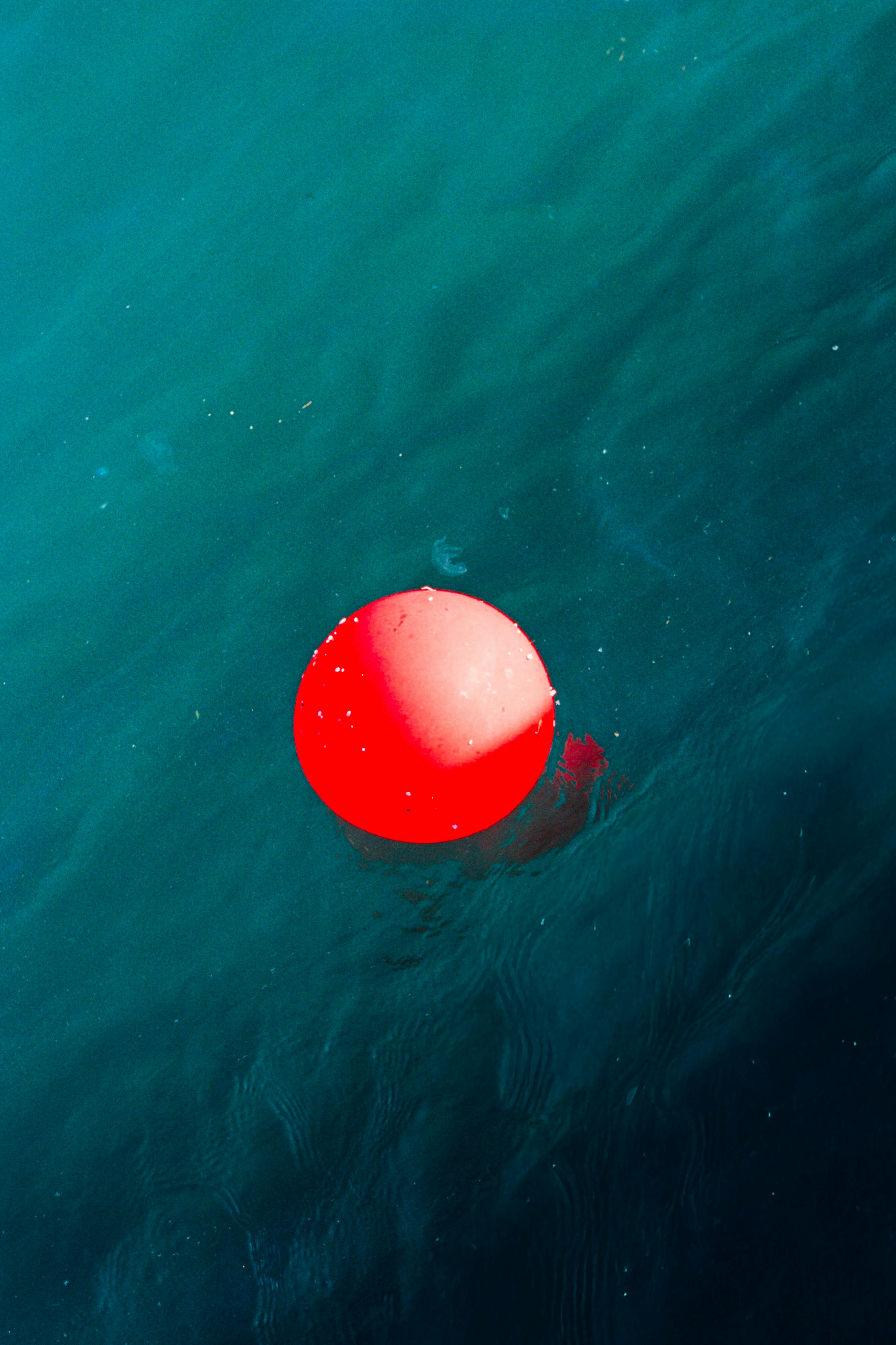 A bright red buoy floating on the surface of deep blue water - 相关推荐