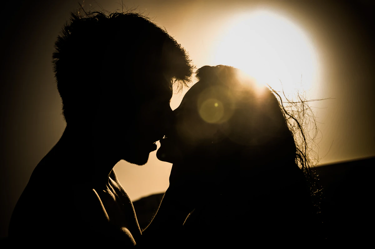 Silhouette d'un couple enlacé à contre-jour devant le soleil couchant
