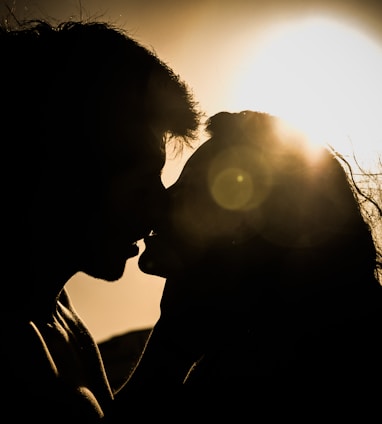 man and woman kissing under the sun