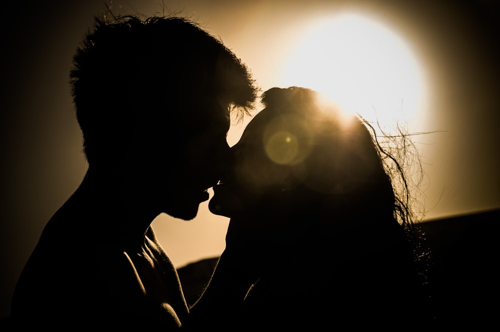 man and woman kissing under the sun